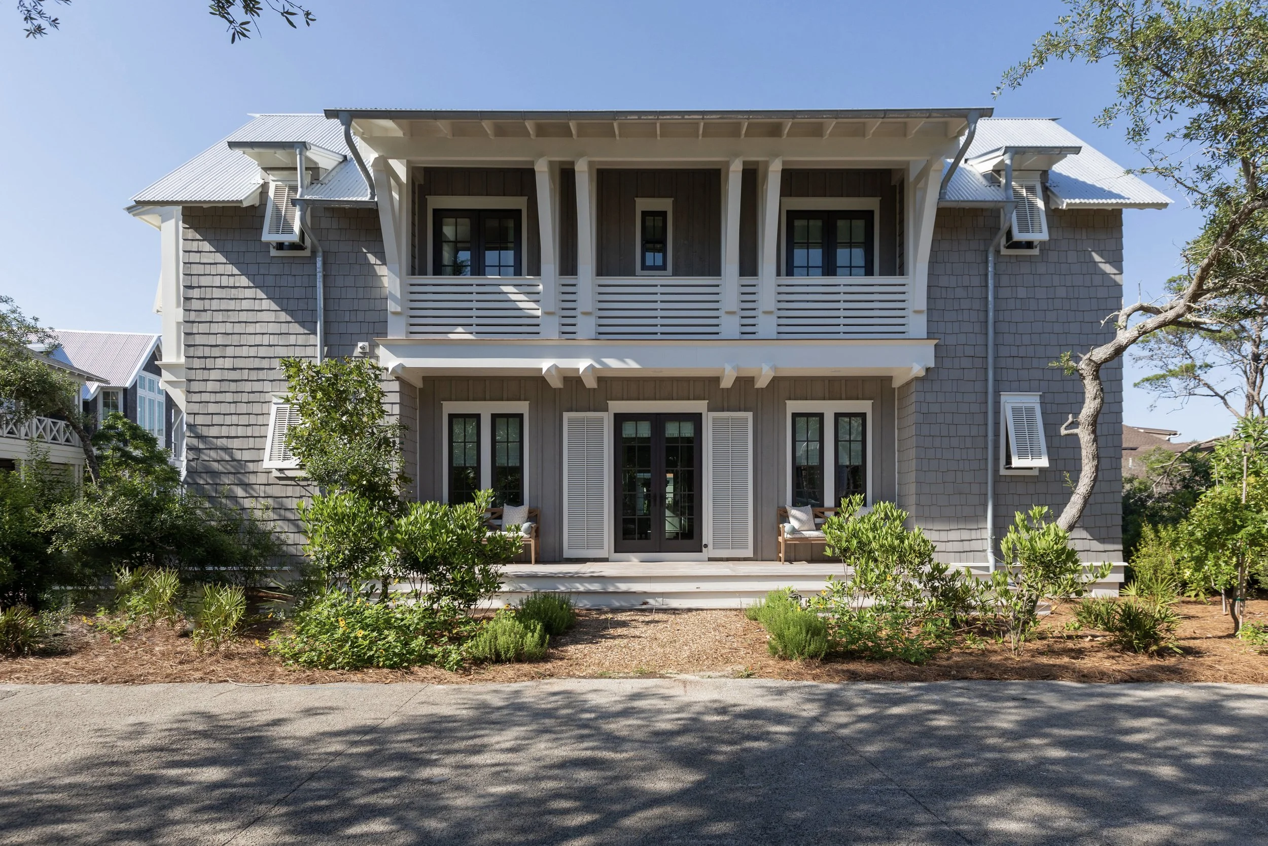 Two-story coastal custom home with covered porches and shingle exterior