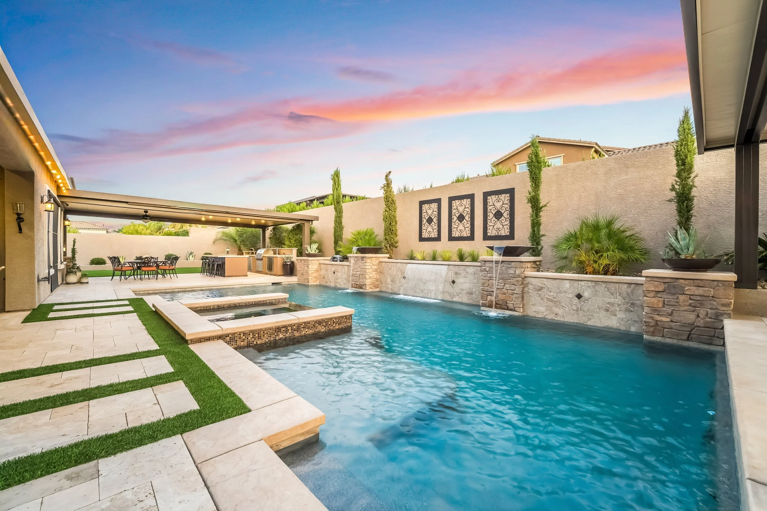 Backyard pool with spa, outdoor furniture, and desert landscaping at sunset