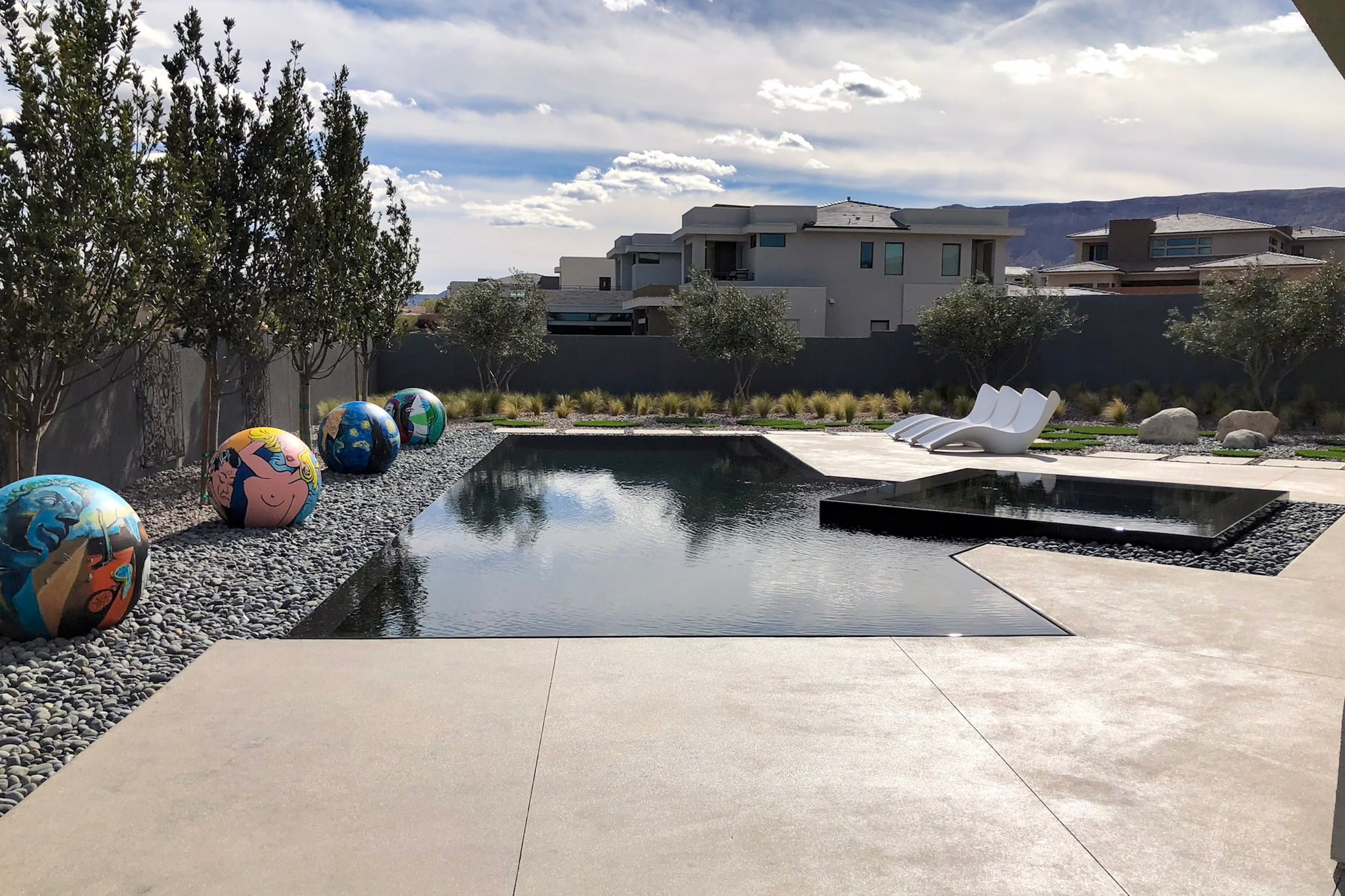 a modern black pebbletec pool in summerlin las vegas that has an infinity edge perimeter overflow with low maintenance landscaping