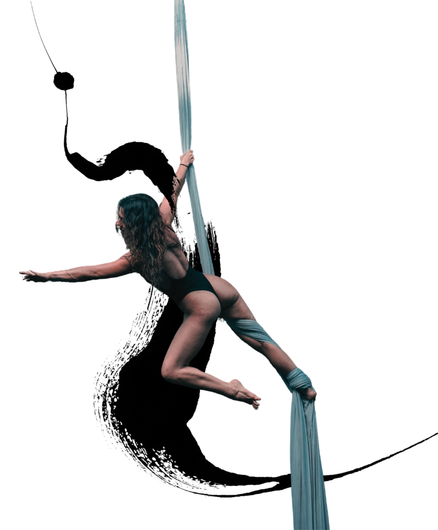 A woman with long, curly hair engaged in aerial silk performance, hanging upside down with her legs wrapped around the fabric and arms extended outward.