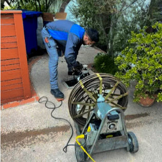 Plumber using professional drain cleaning equipment under a kitchen sink
