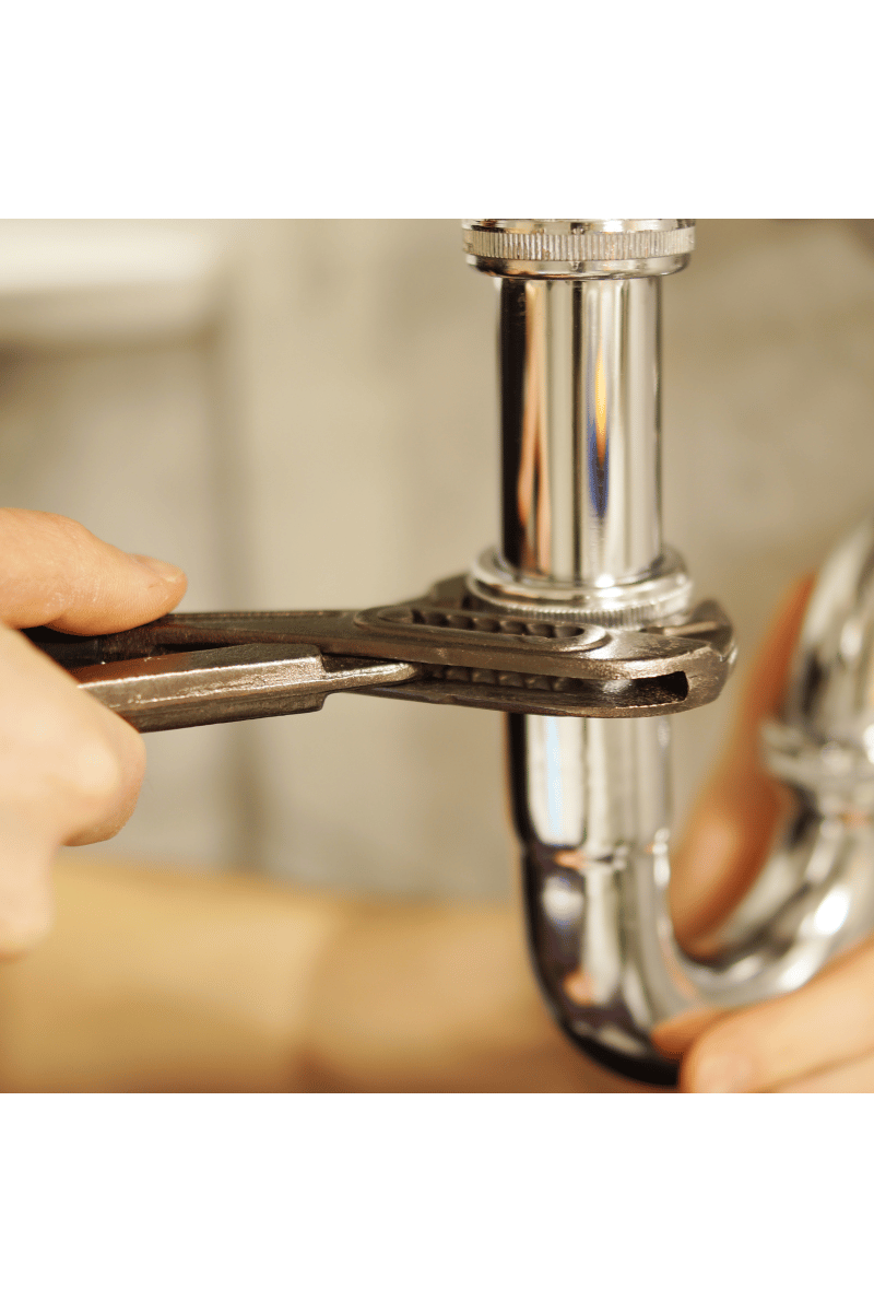 Plumber tightening a faucet pipe with a wrench during a plumbing repair