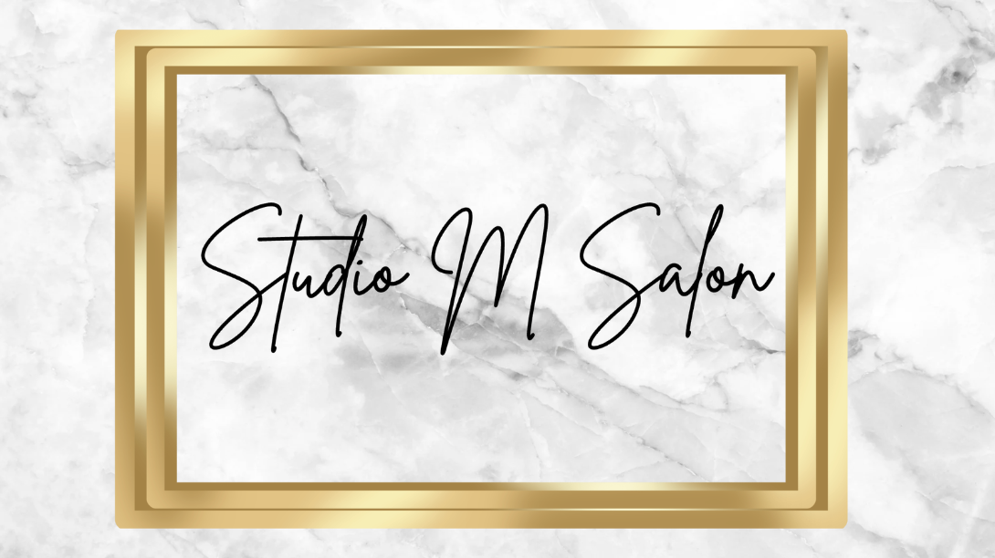 Sign reading 'Studio M Salon' on a marble background with a gold double border.