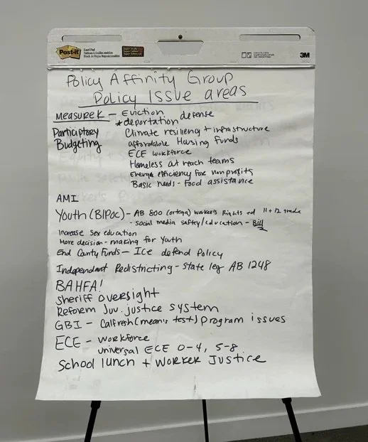Handwritten notes on a whiteboard discussing policy issues such as Measure 2, decriminalizing defiance, climate resilience, affordable housing, homelessness, youth rights, bail reform, sheriff oversight, and education policies.
