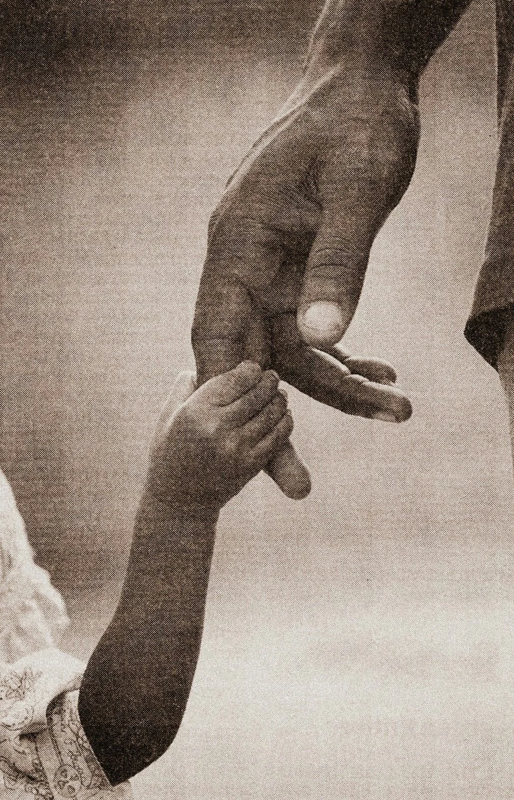 A black and white photograph showing a large adult hand holding a small child's hand, with the child's hand gently gripping the adult's finger.