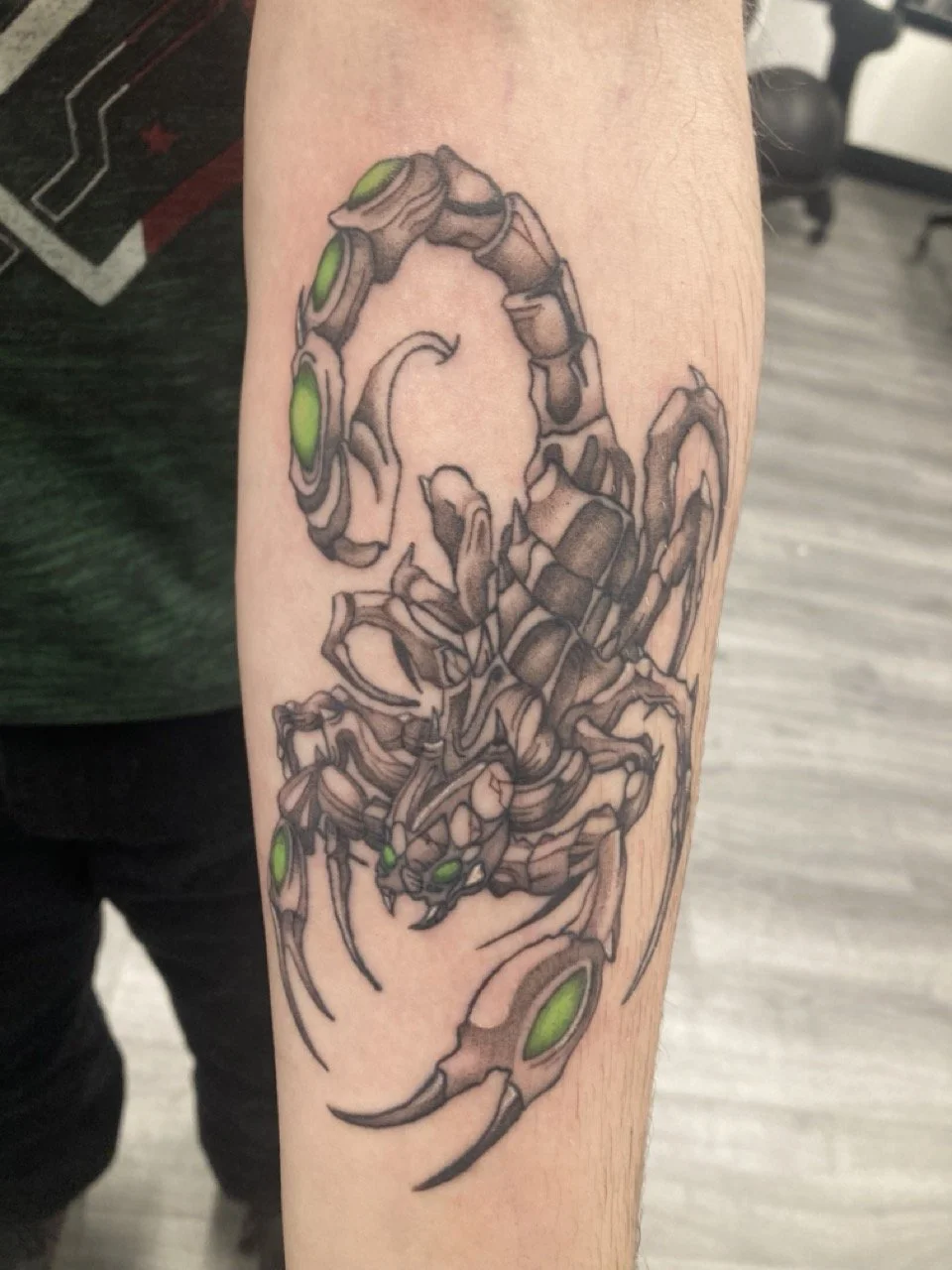 Tattoo of a scorpion with green ink on a person's arm. Color Tattoo.