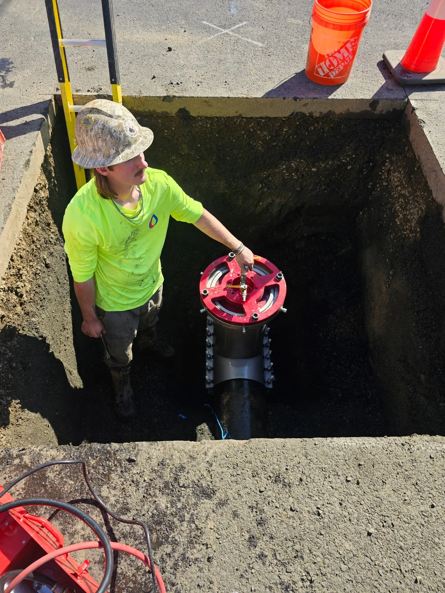 A&A Drilling worker installing a valve insertion on the side of a road.