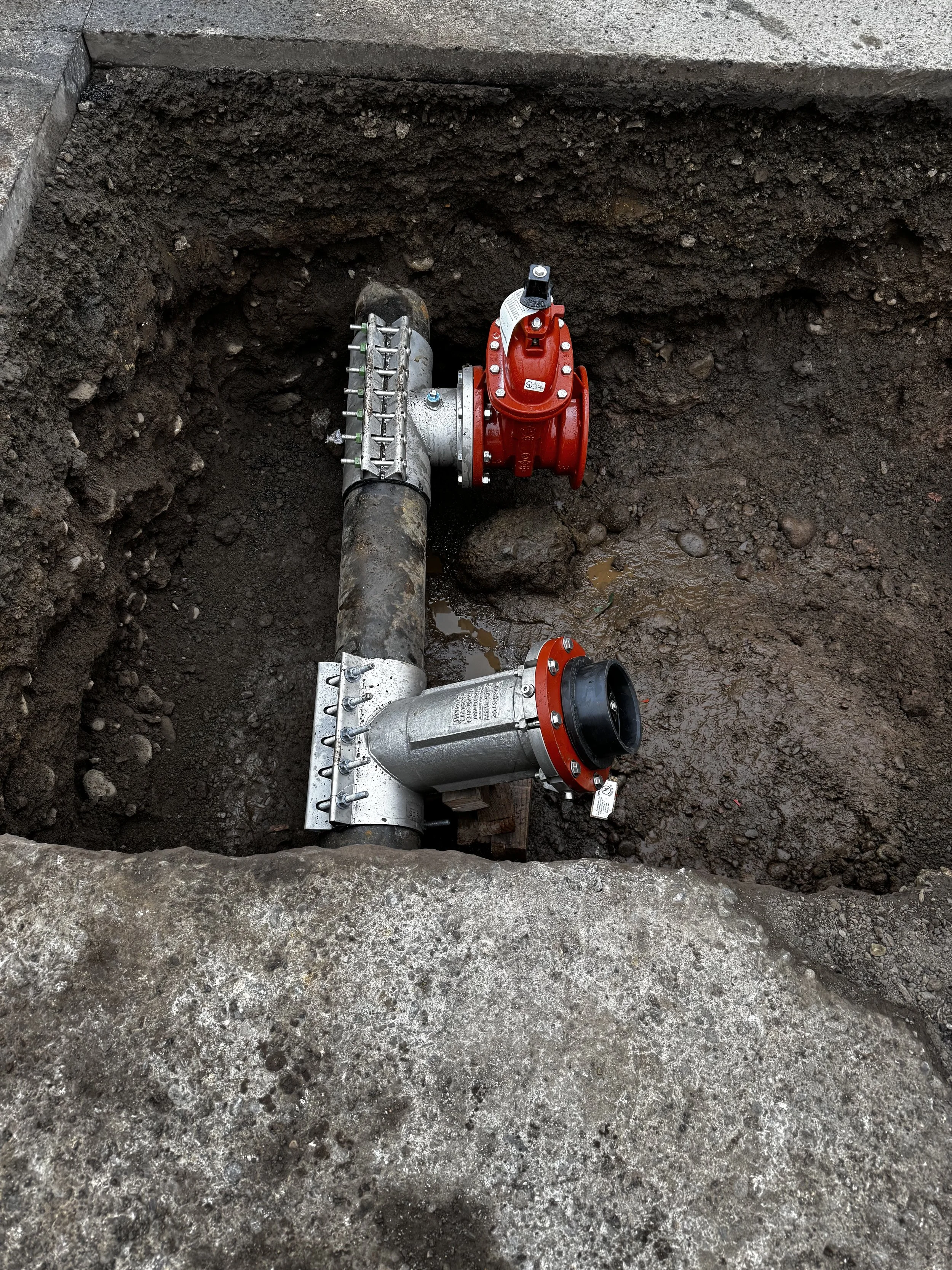 Underground valve insertion on a dirt excavation site.