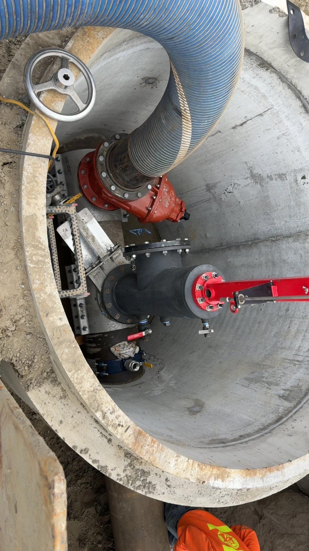 Installation of underground piping with large pipes and valves inside a concrete manhole.
