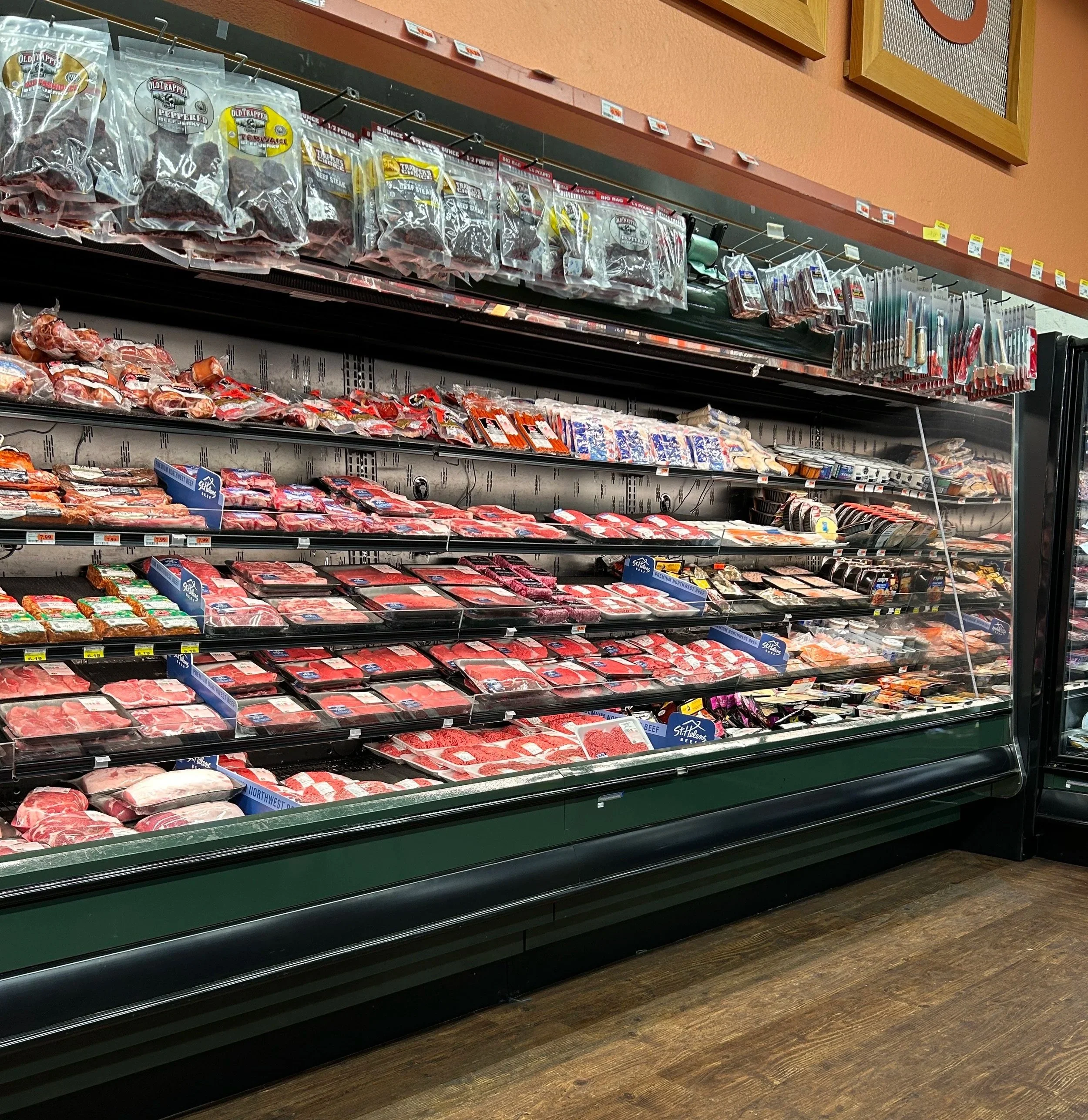 Refrigerated meat and poultry packages on store shelves in a grocery store.