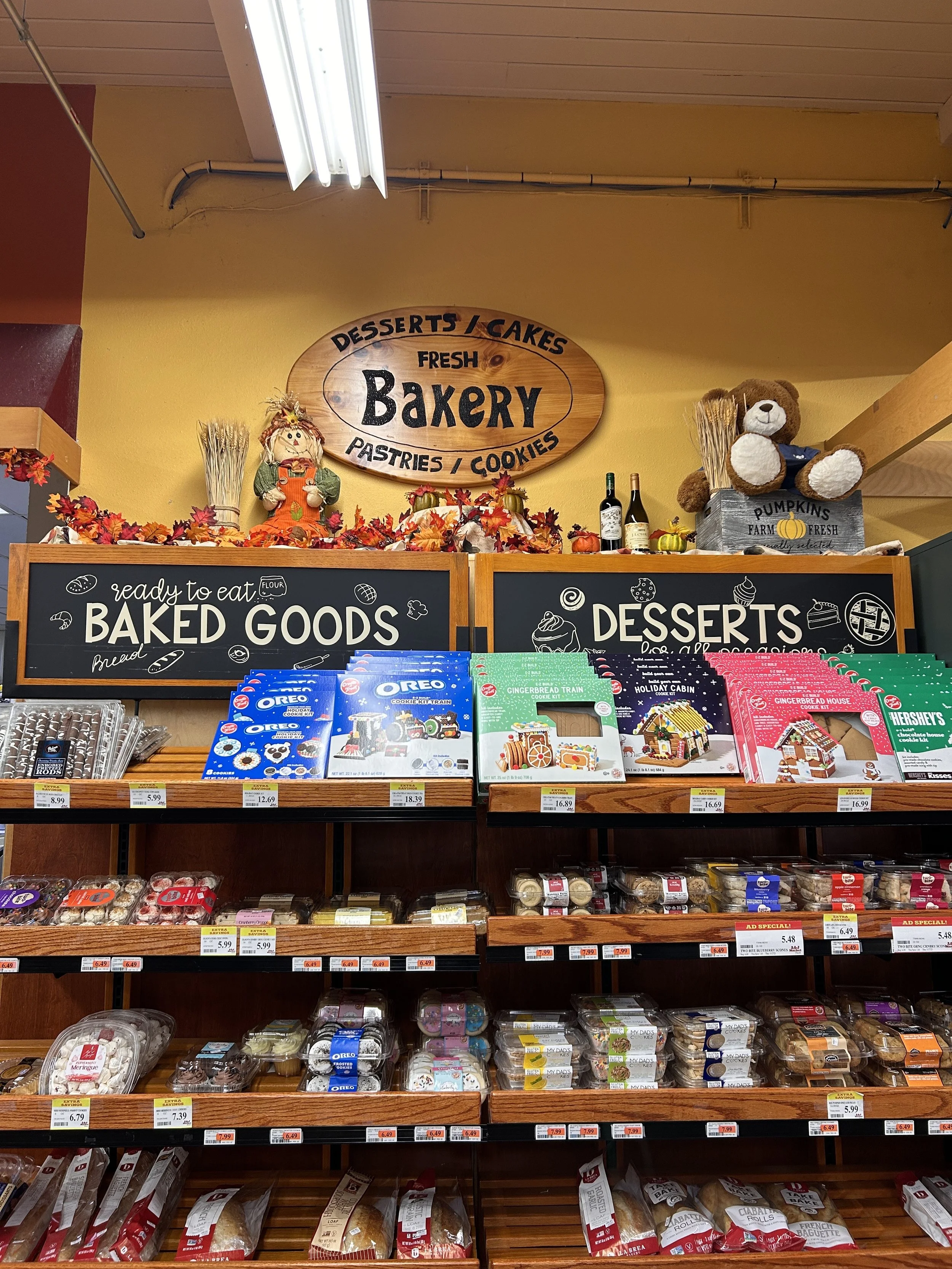Shelves with various containers and boxes of baked goods, cookies, and pastries in a bakery display.