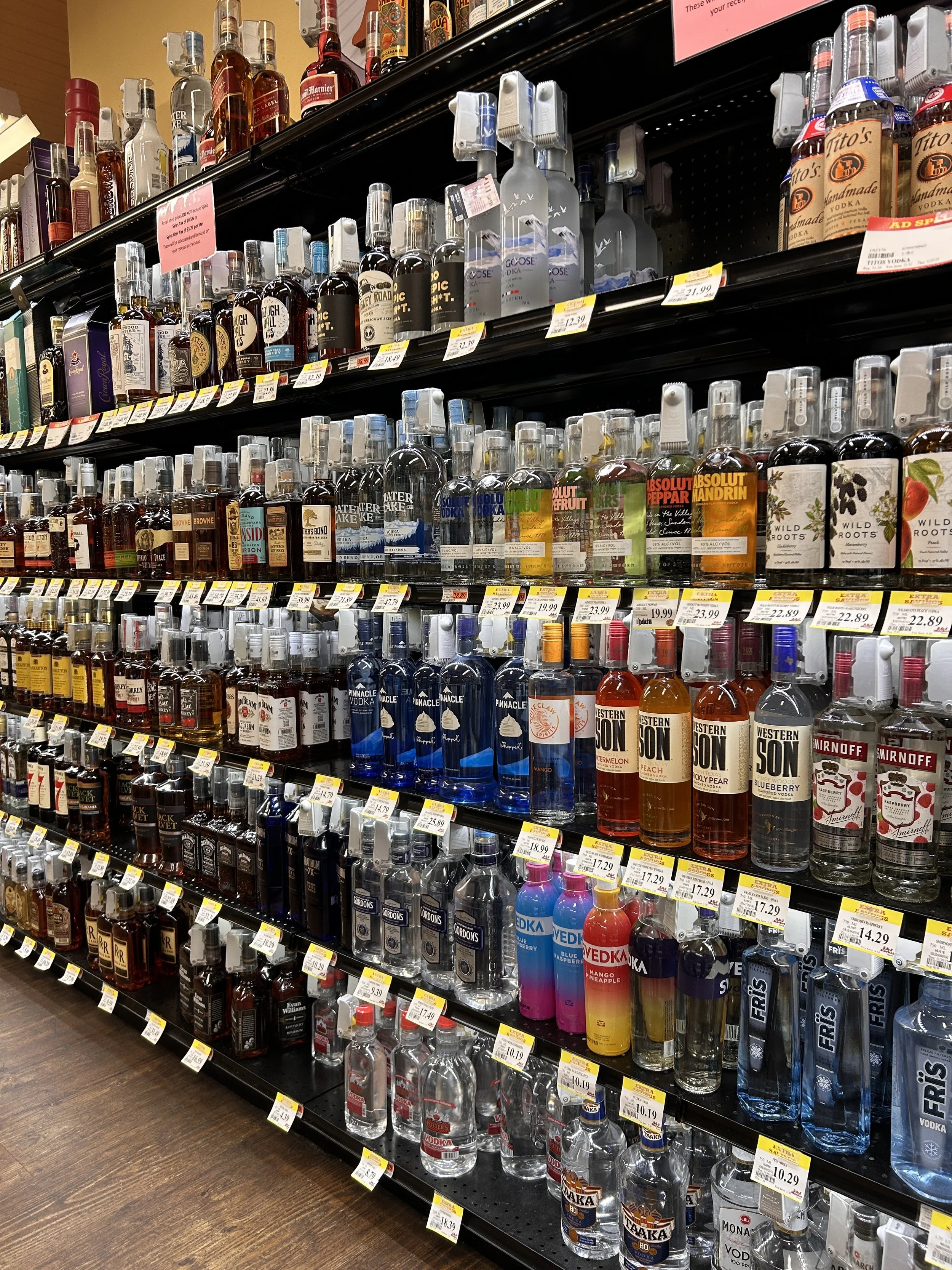Shelves stocked with various bottles of alcohol in a liquor store.