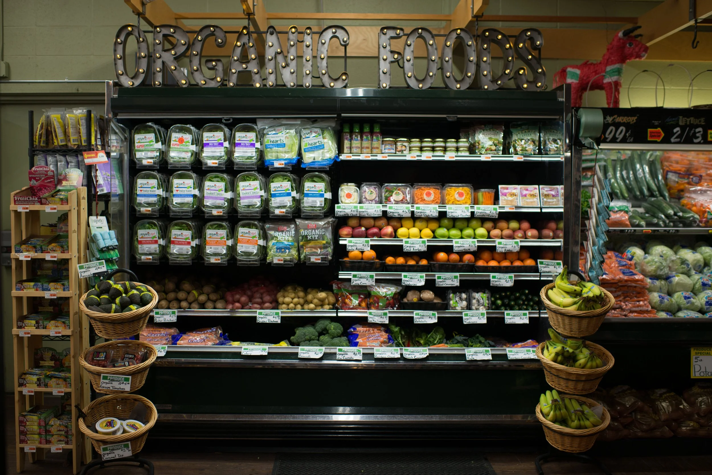 Shelf display of organic fruits including apples, oranges, and lemons in a grocery store.