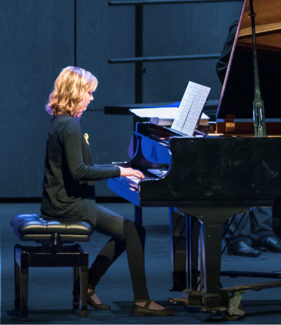 Two men in tuxedos shaking hands on stage during an award ceremony or formal event.