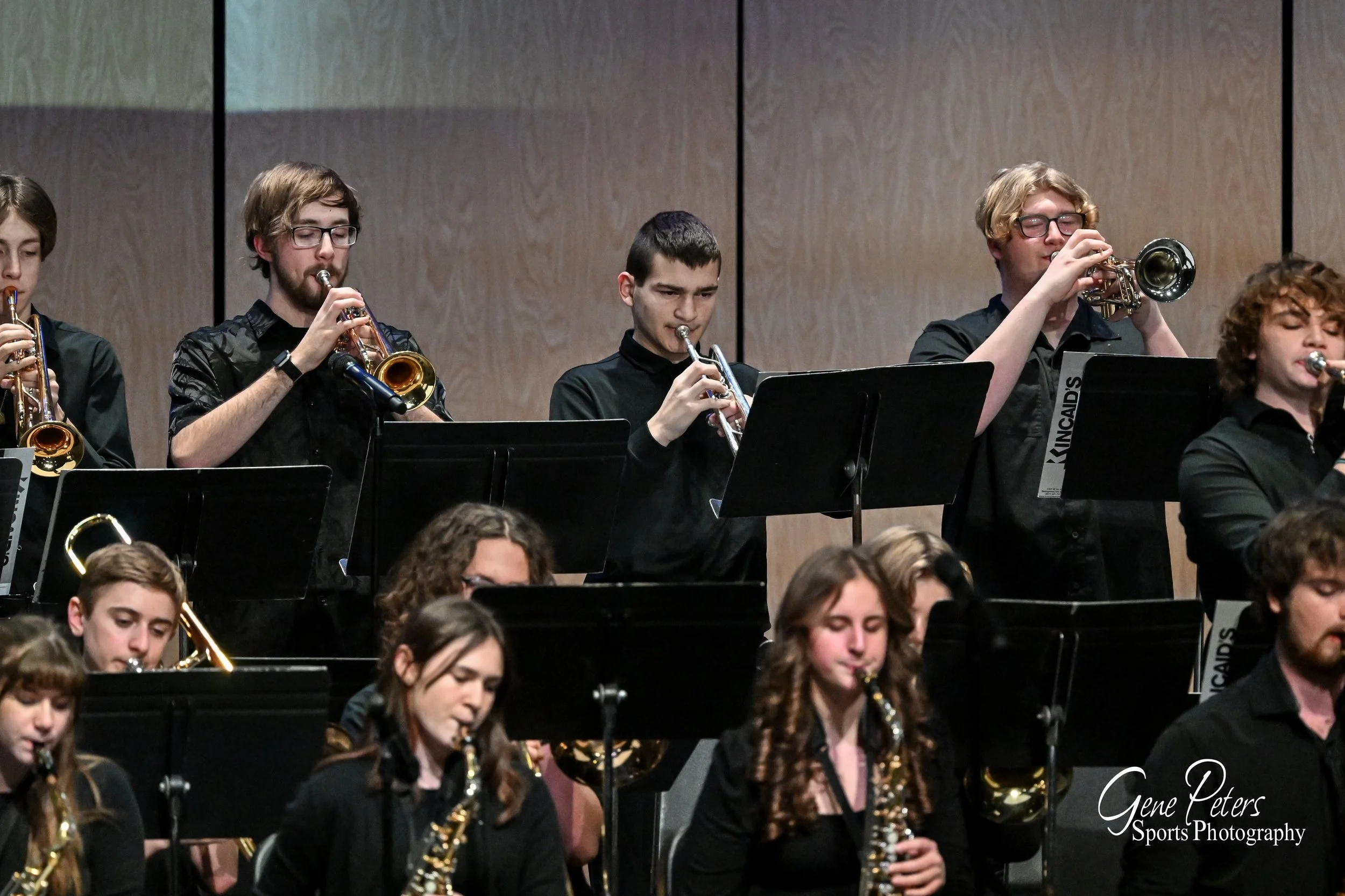 Students playing wind instruments in a band or orchestra performance.