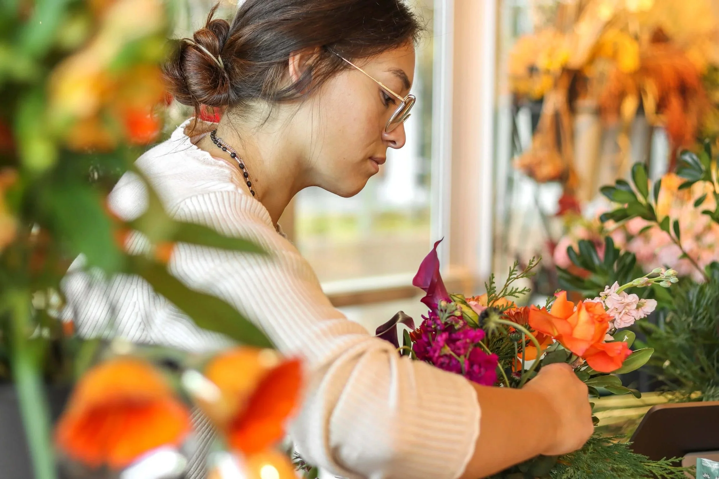 Ari assembling a bouquet of pink and orange flowers.