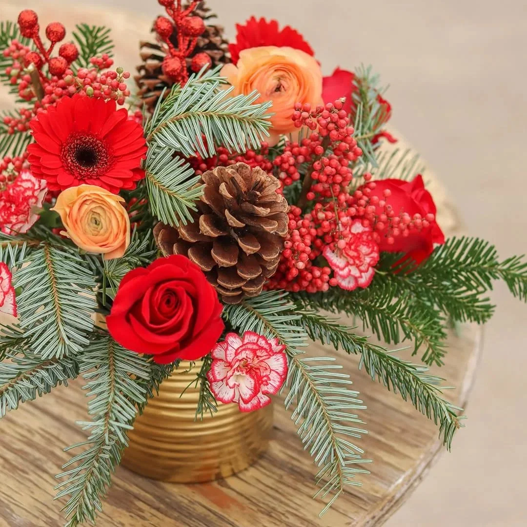 pine branches, gerber daisies, red roses, red berries and pine cones.