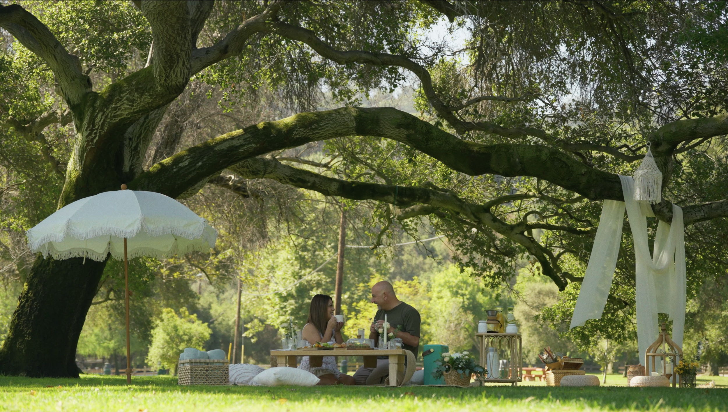 Couple relaxing at an outdoor picnic date with white parasol — Mandra Soul
