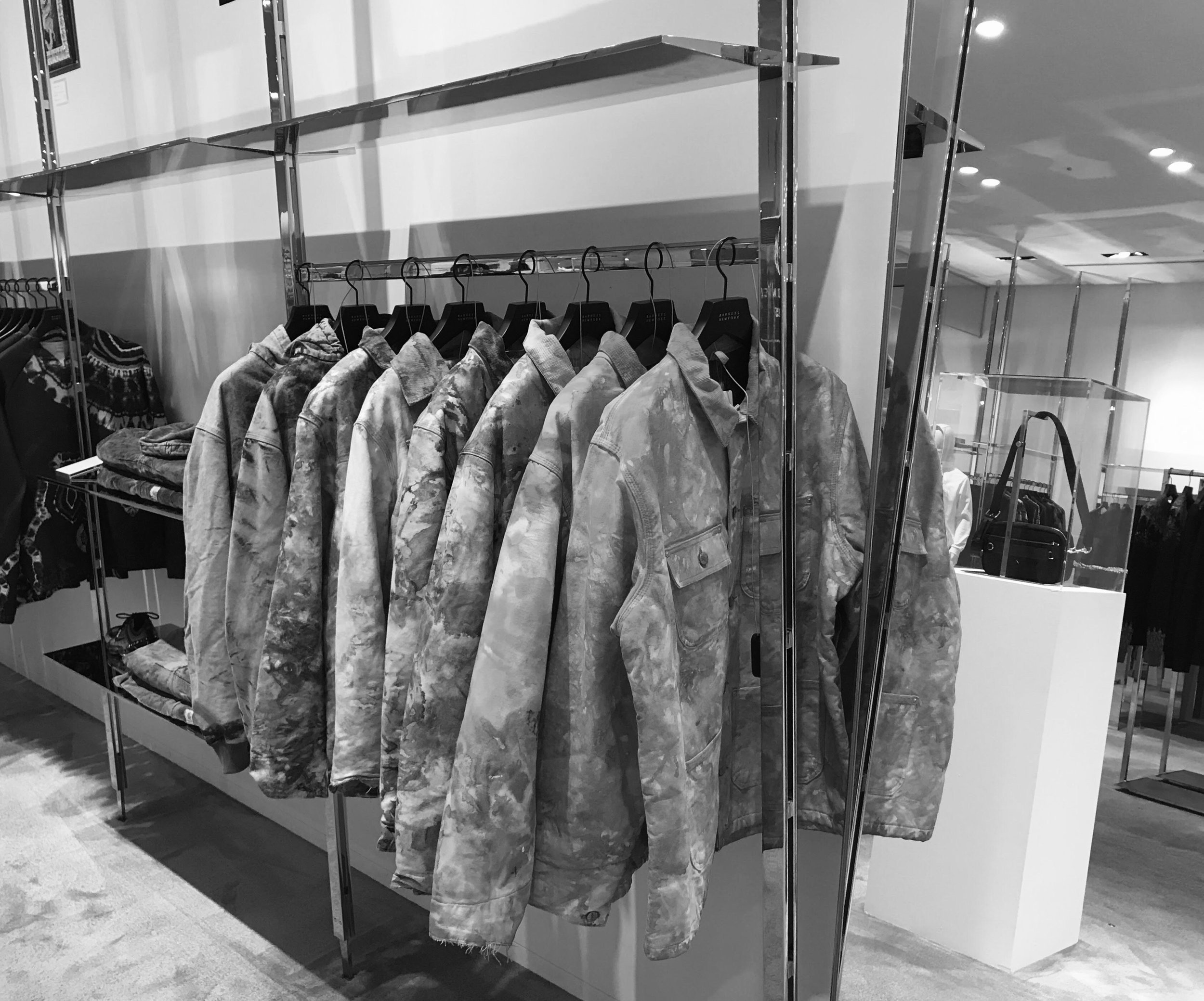 A rack of camouflage jackets hanging in a retail clothing store.