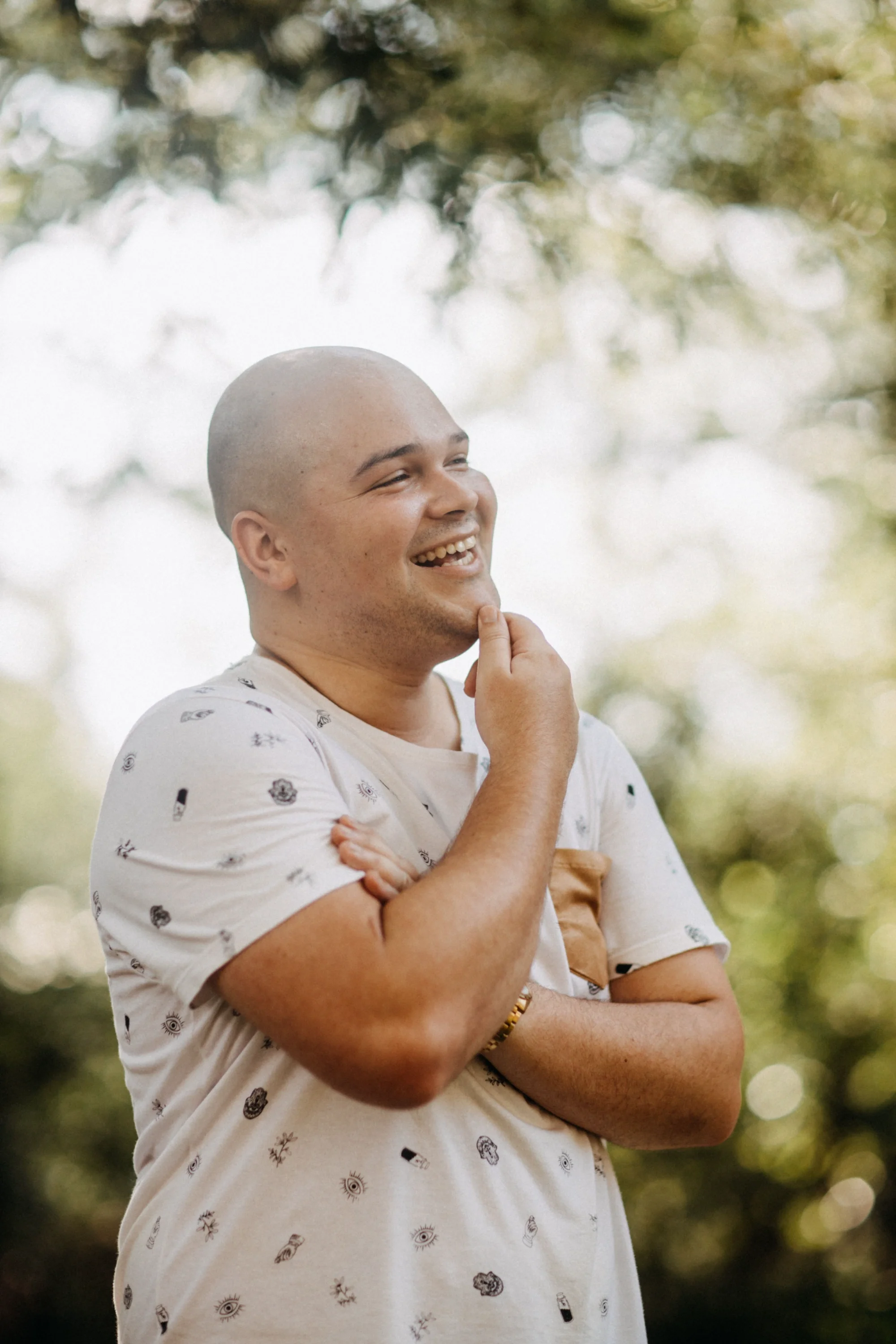 A man smiling with his hand on his chin, outside.
