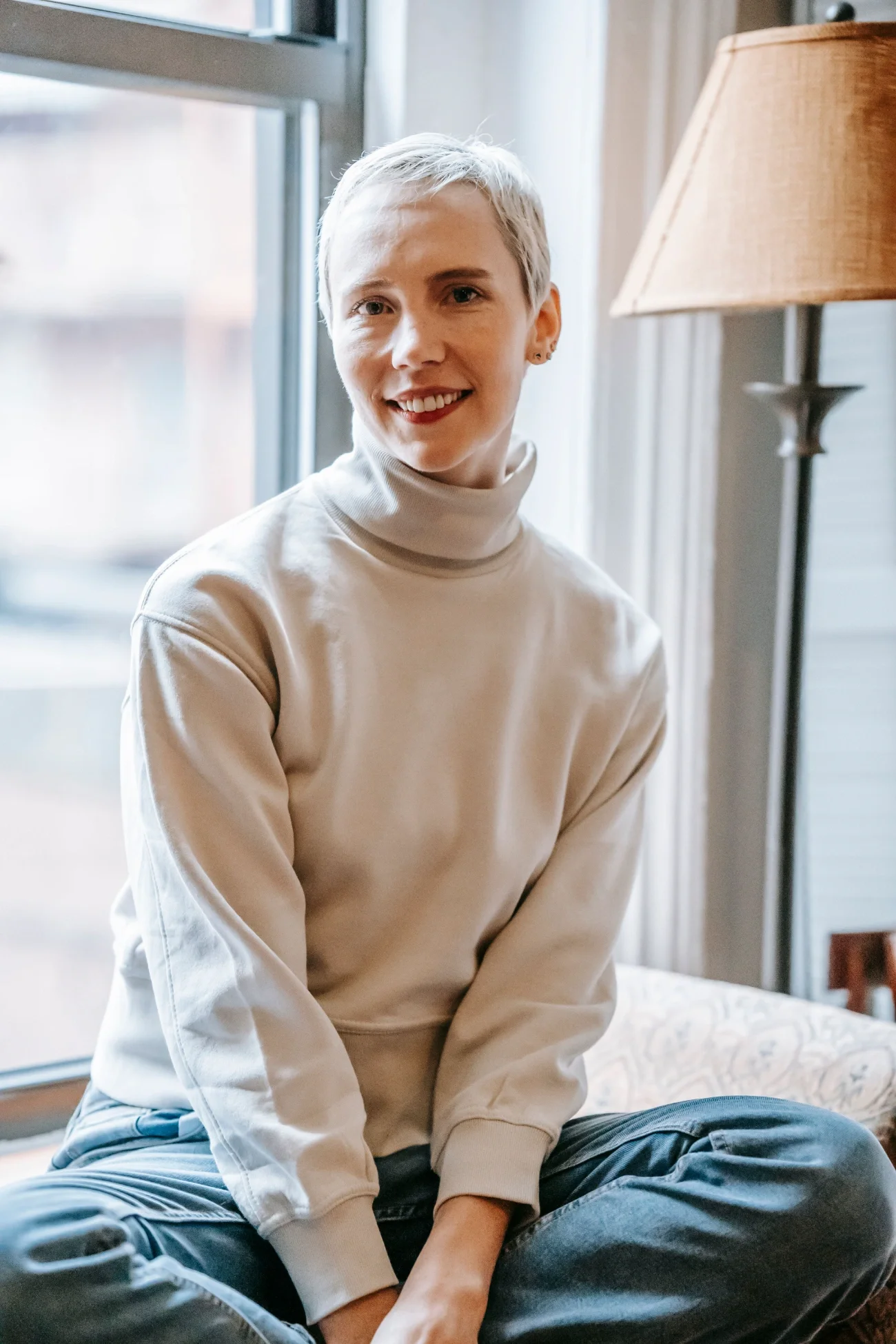 A woman with short hair wearing a turtleneck smiling at the camera.