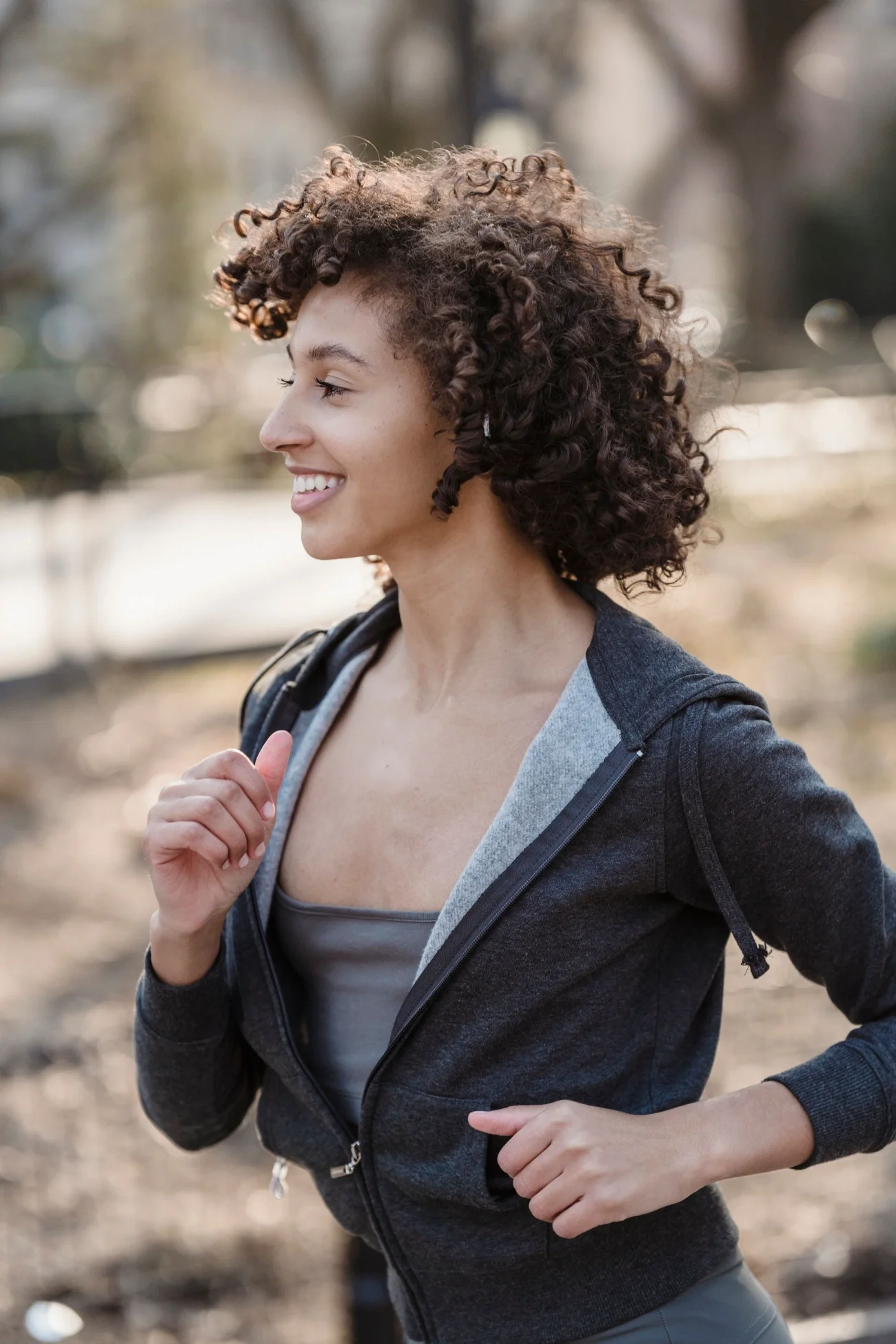 A woman smiling and running on an outdoor path.