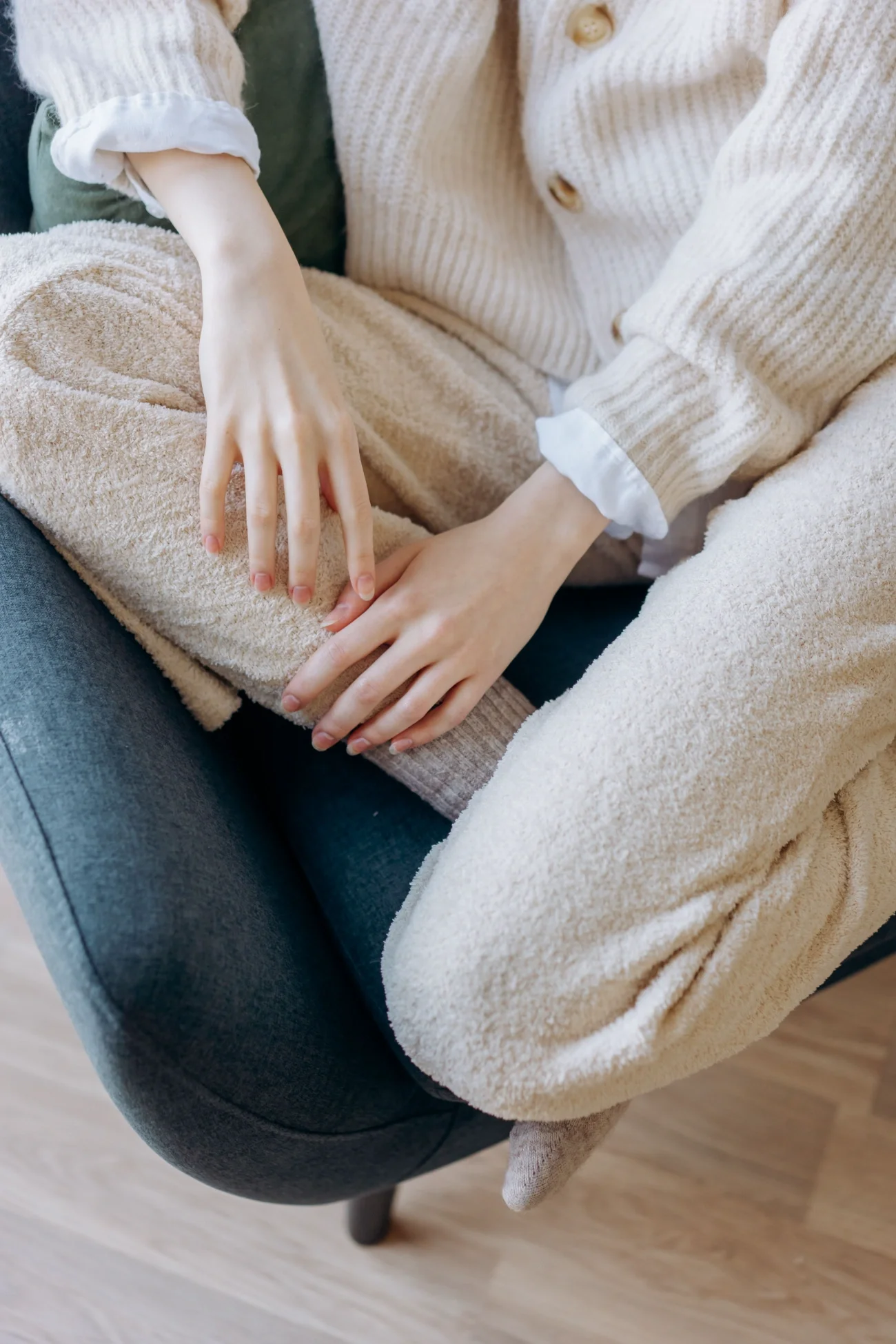 A woman sitting on a dark coloured couch in a cozy outfit.