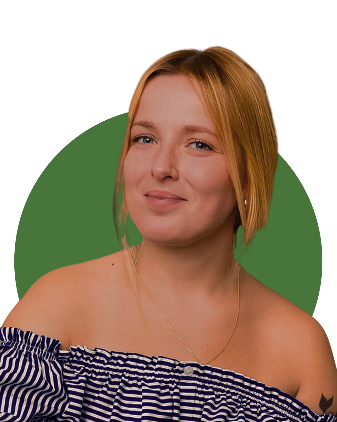 A young woman with blonde hair and blue eyes smiling while wearing an off-shoulder striped top and a necklace, in a cozy home setting with plants and framed pictures in the background.