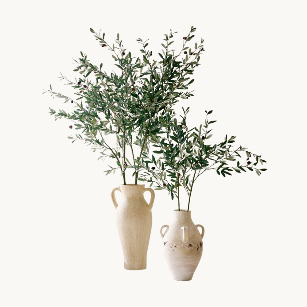 Two beige vases with greenery and small dark berries against a plain white background.