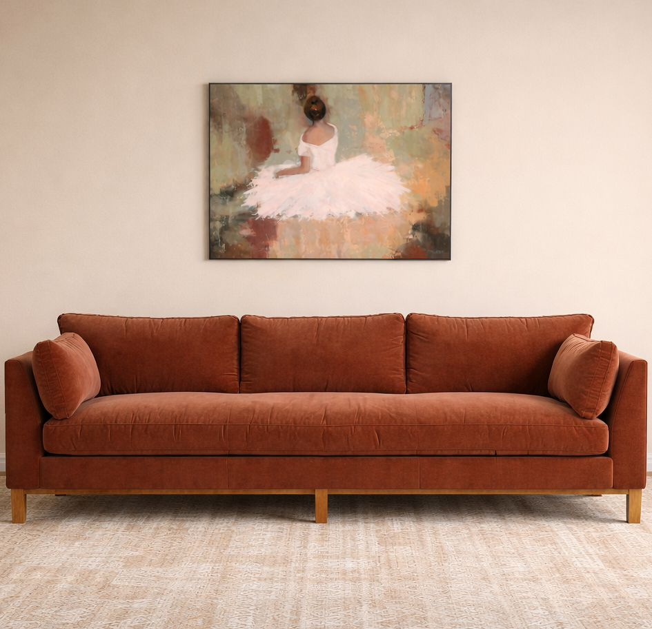 A burnt orange sofa with two matching pillows in front of a beige wall.