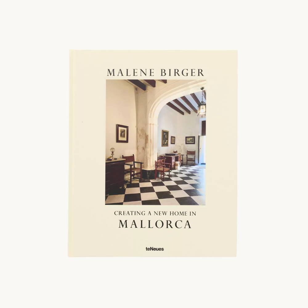 Book titled "Creating a New Home in Mallorca" by Malene Birger, featuring a photo of an interior with black and white checkered floor, white walls, wooden ceiling beams, and framed artwork.