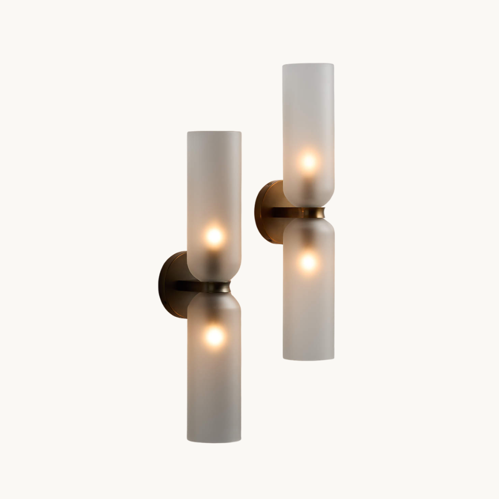 A modern double wall sconce with frosted glass shades and a brass finish, mounted on a plain white background.