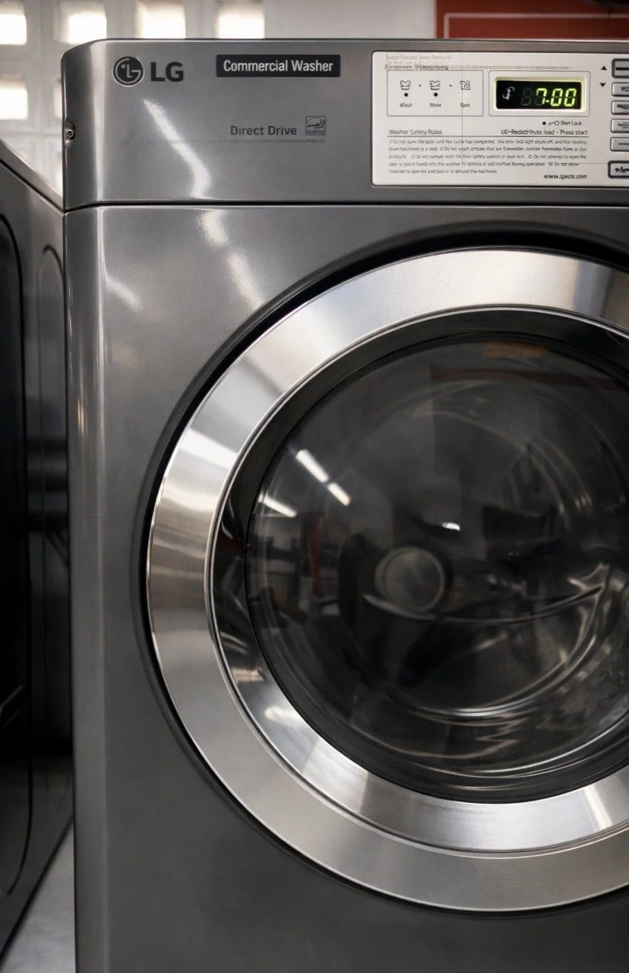 Lavadora de ropa eléctrica de color gris con puerta de vidrio, marca LG, programa de lavado en progreso a 70 grados Celsius