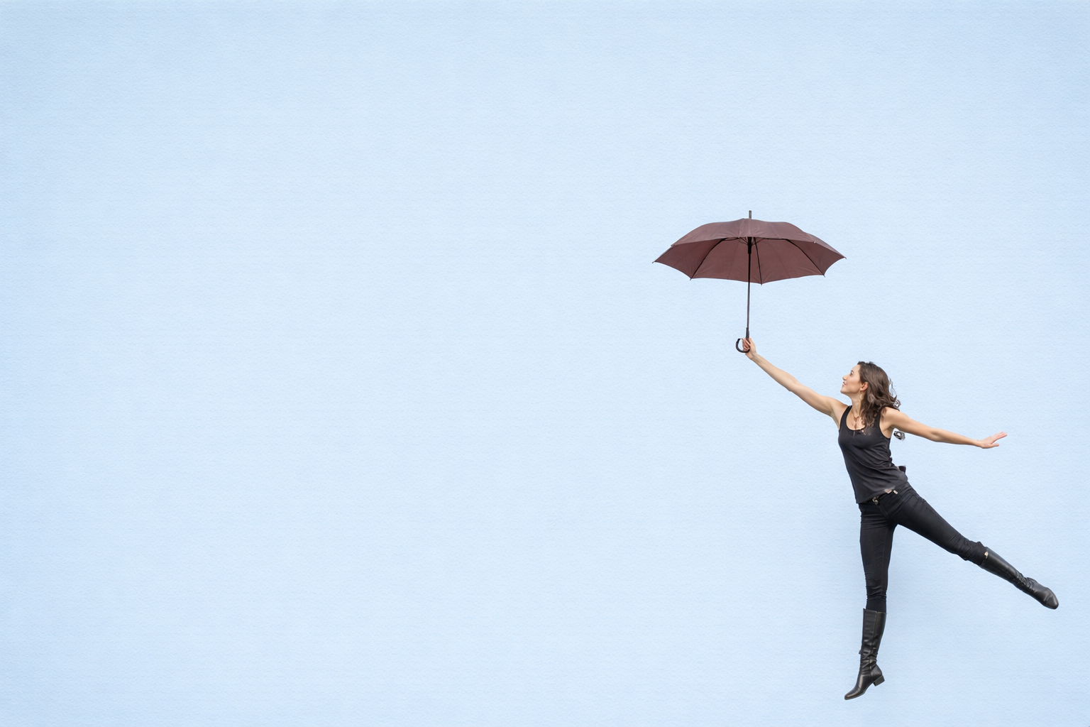 Person holding an umbrella against a yellow wall, symbolizing balance, uncertainty, and navigating workplace challenges with clarity.