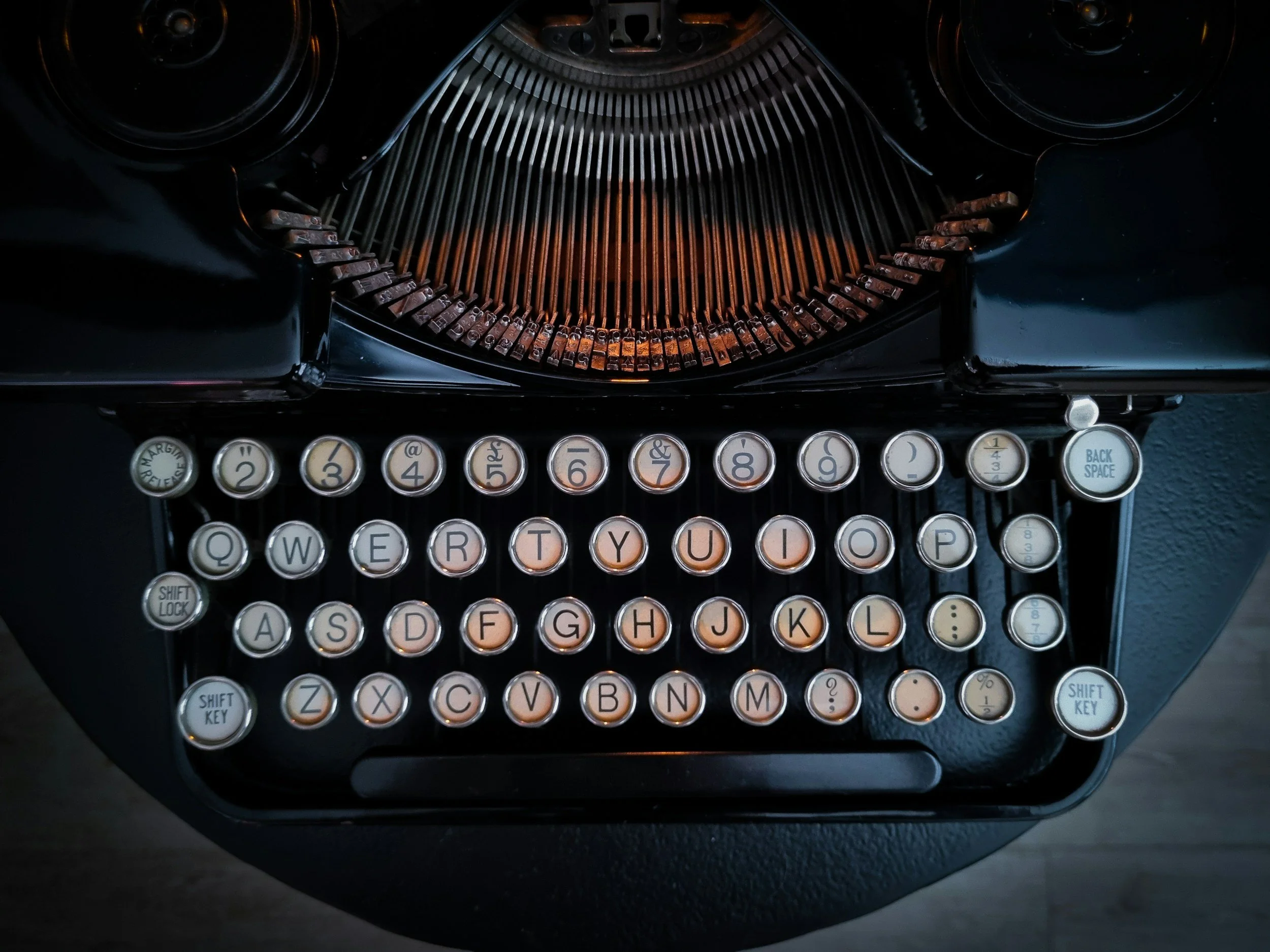 Close-up of a vintage black typewriter with round cream keys and black letters.