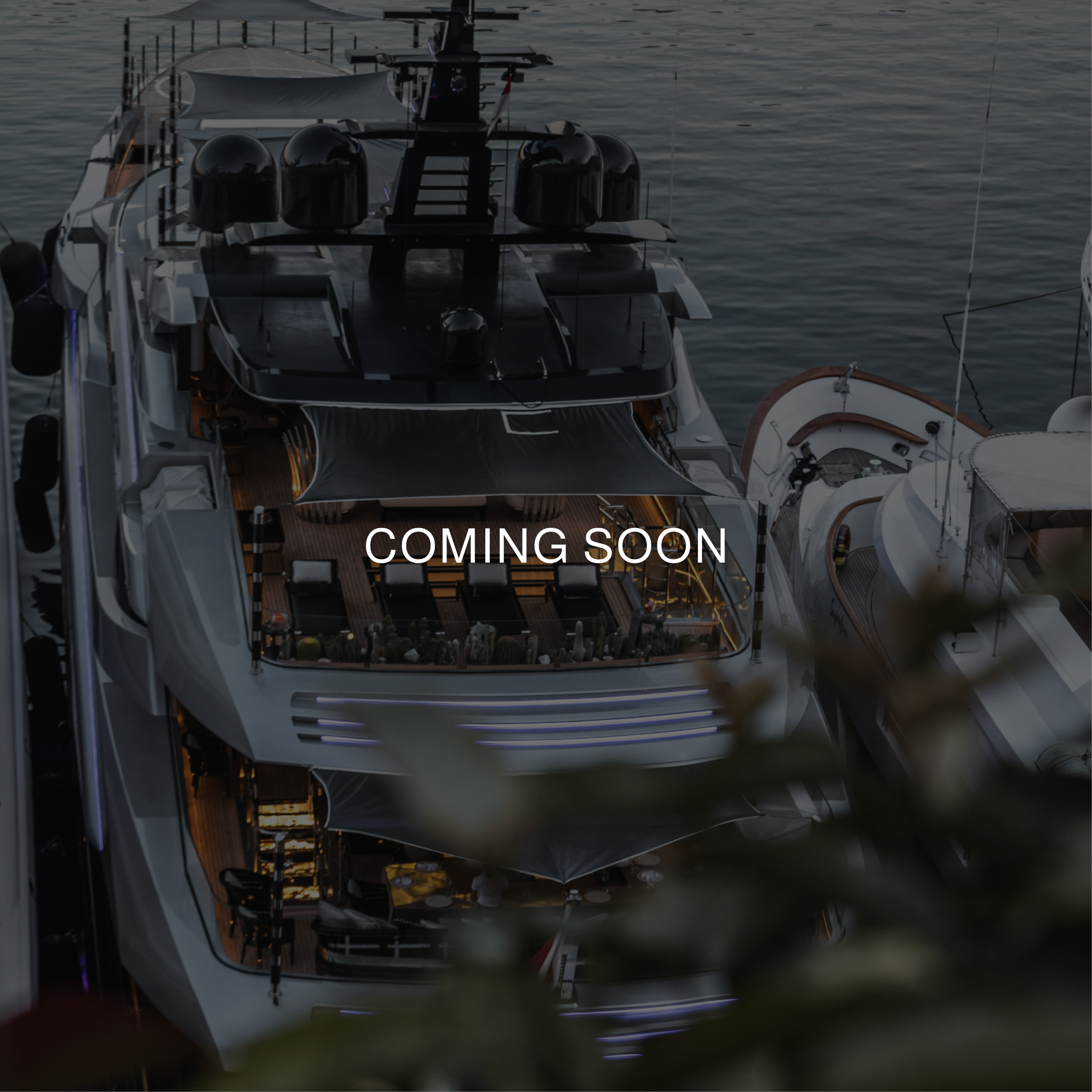Yate de lujo amarrado en un puerto, con la leyenda 'COMING SOON' superpuesta en el centro.