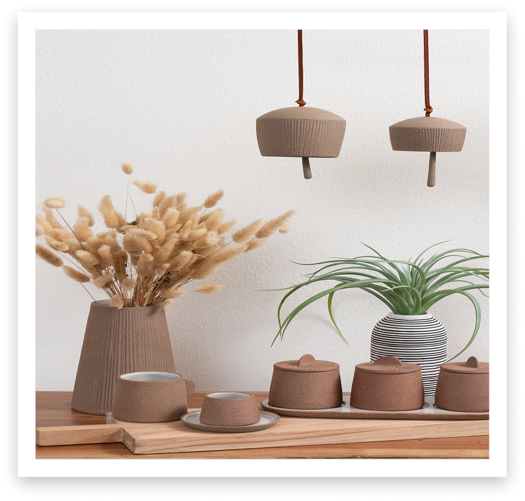 Decoración con jarrones de cerámica, plantas y lámparas colgantes en un mueble de madera.