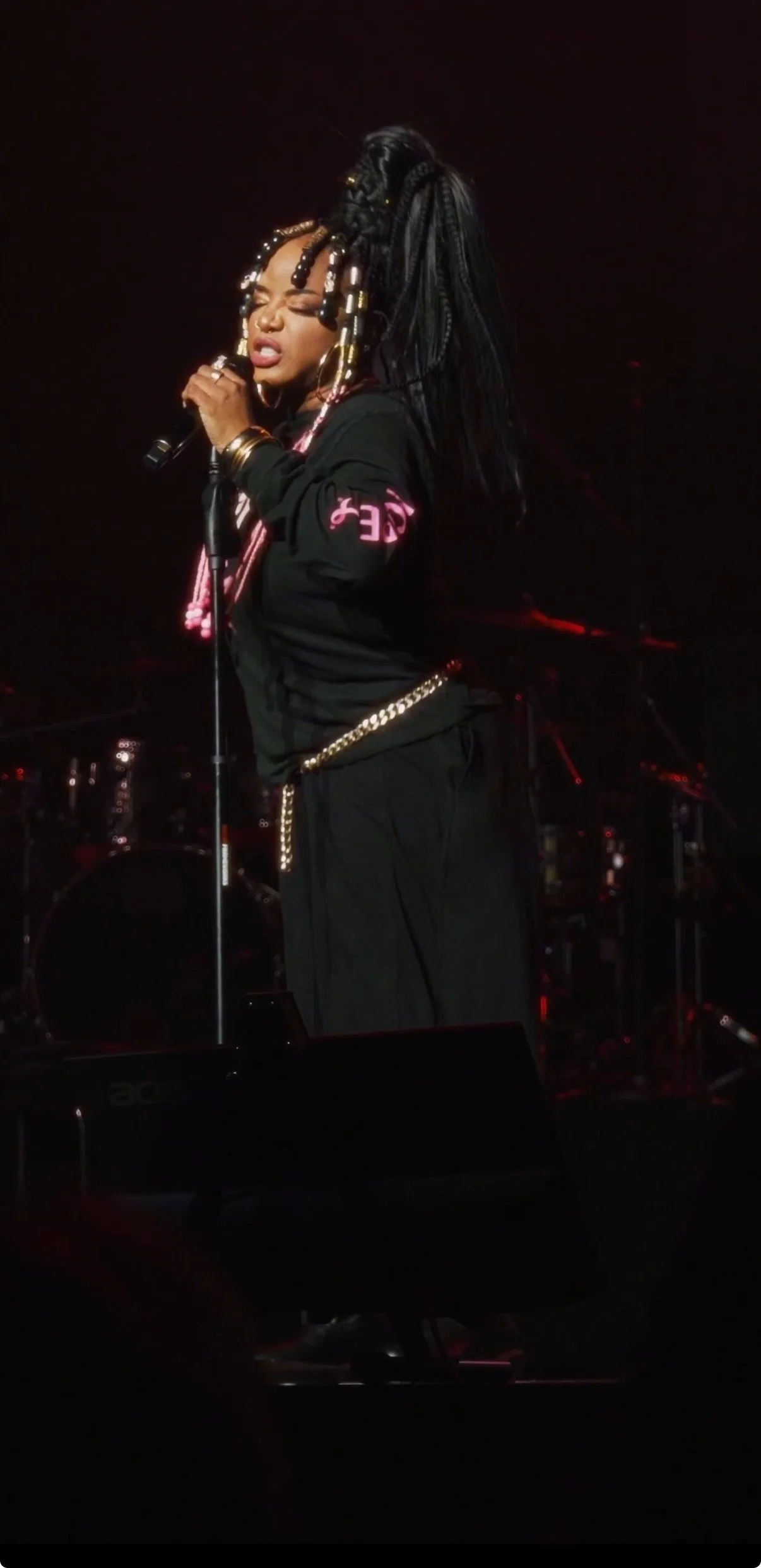 A black Woman singing at a microphone during a concert