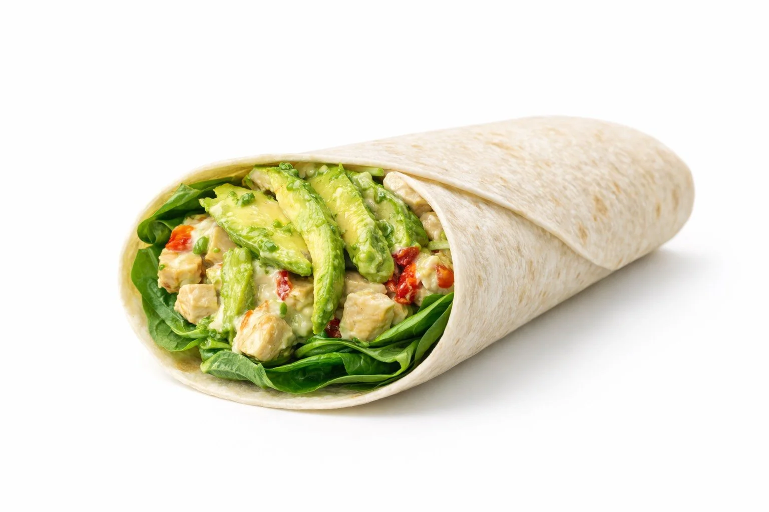 Close-up of a chicken and avocado salad wrap with lettuce, chopped chicken, avocado slices, and diced tomatoes inside a white flour tortilla.