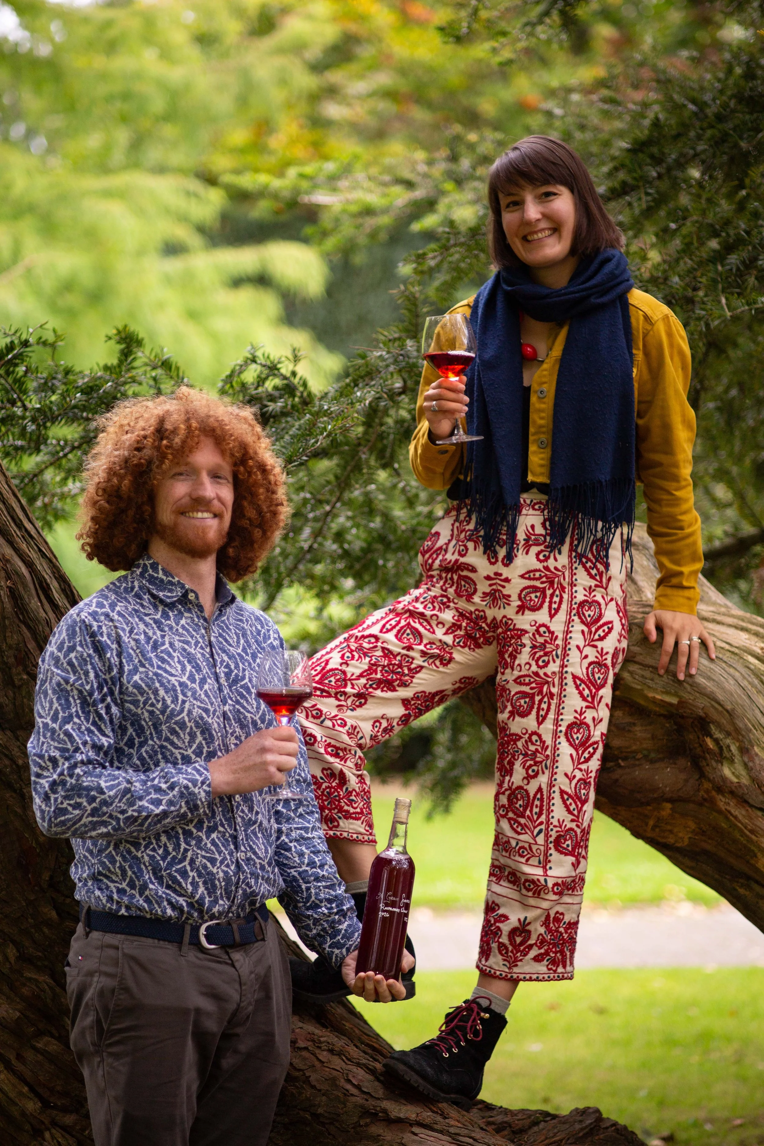 Winemakers Gretchen and Alan sitting against a large tree with glasses of wine in their hands