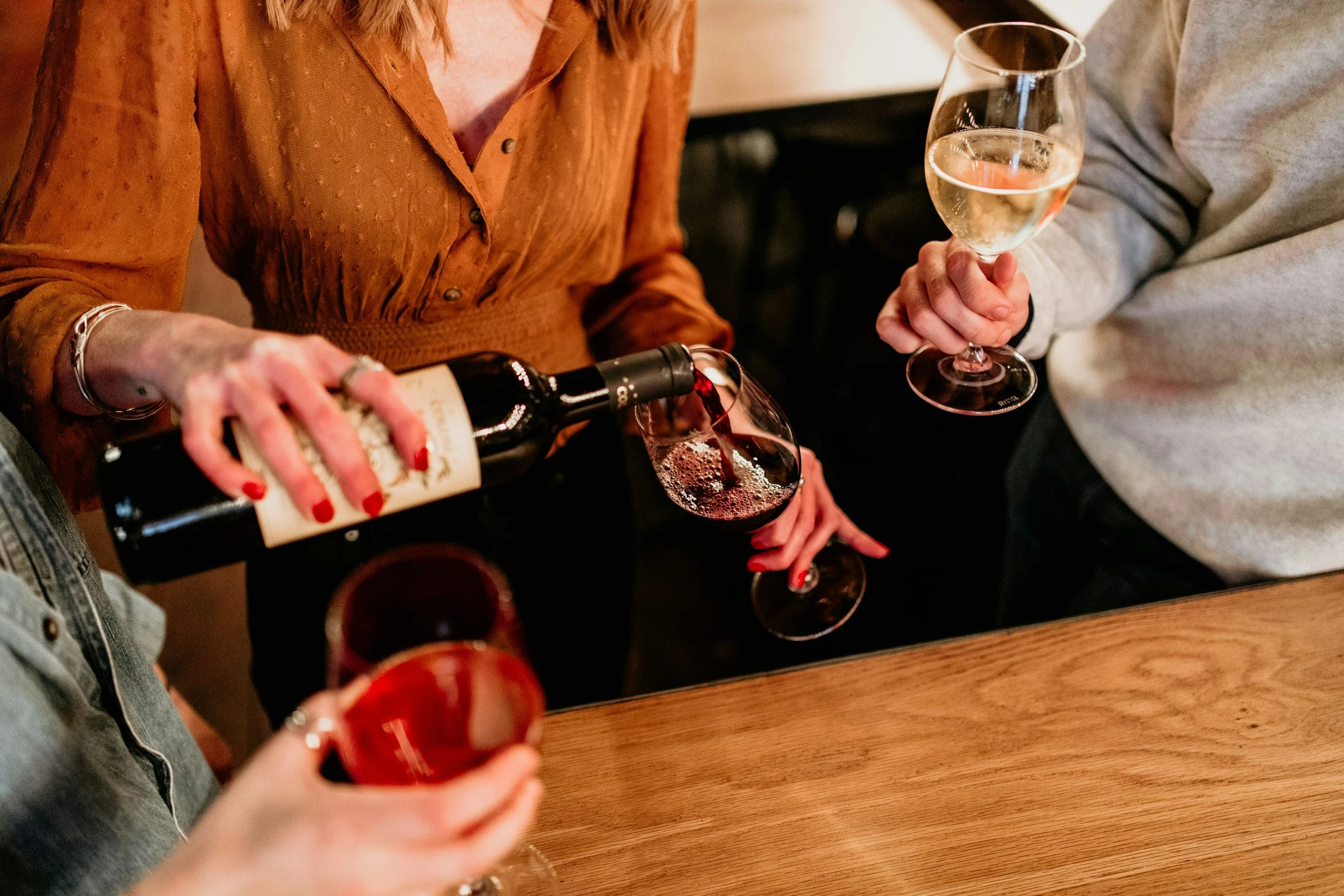 People sharing a bottle of white wine and glasses in a social setting.