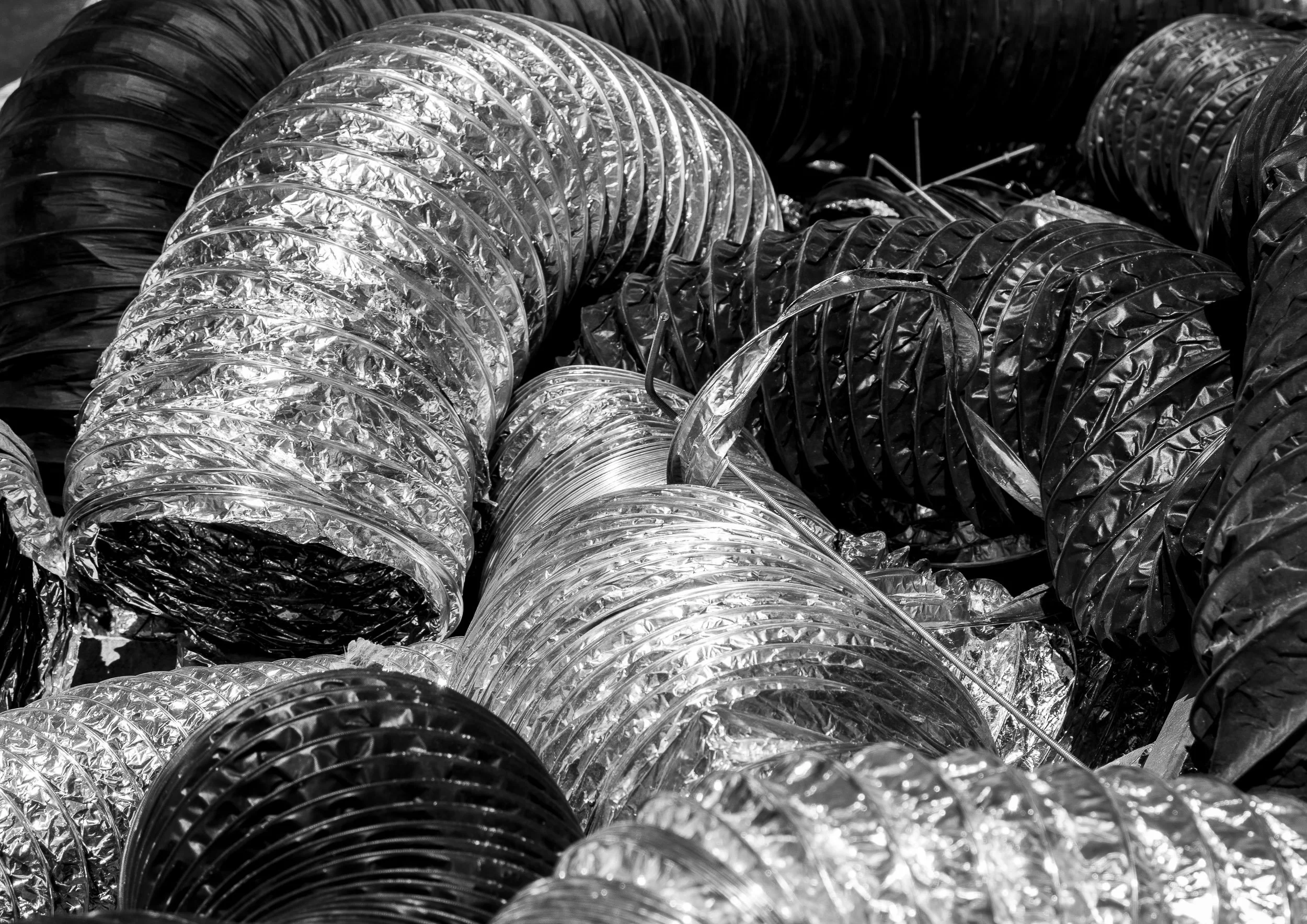 Variedad de tubos flexibles de diferentes colores y materiales apilados.