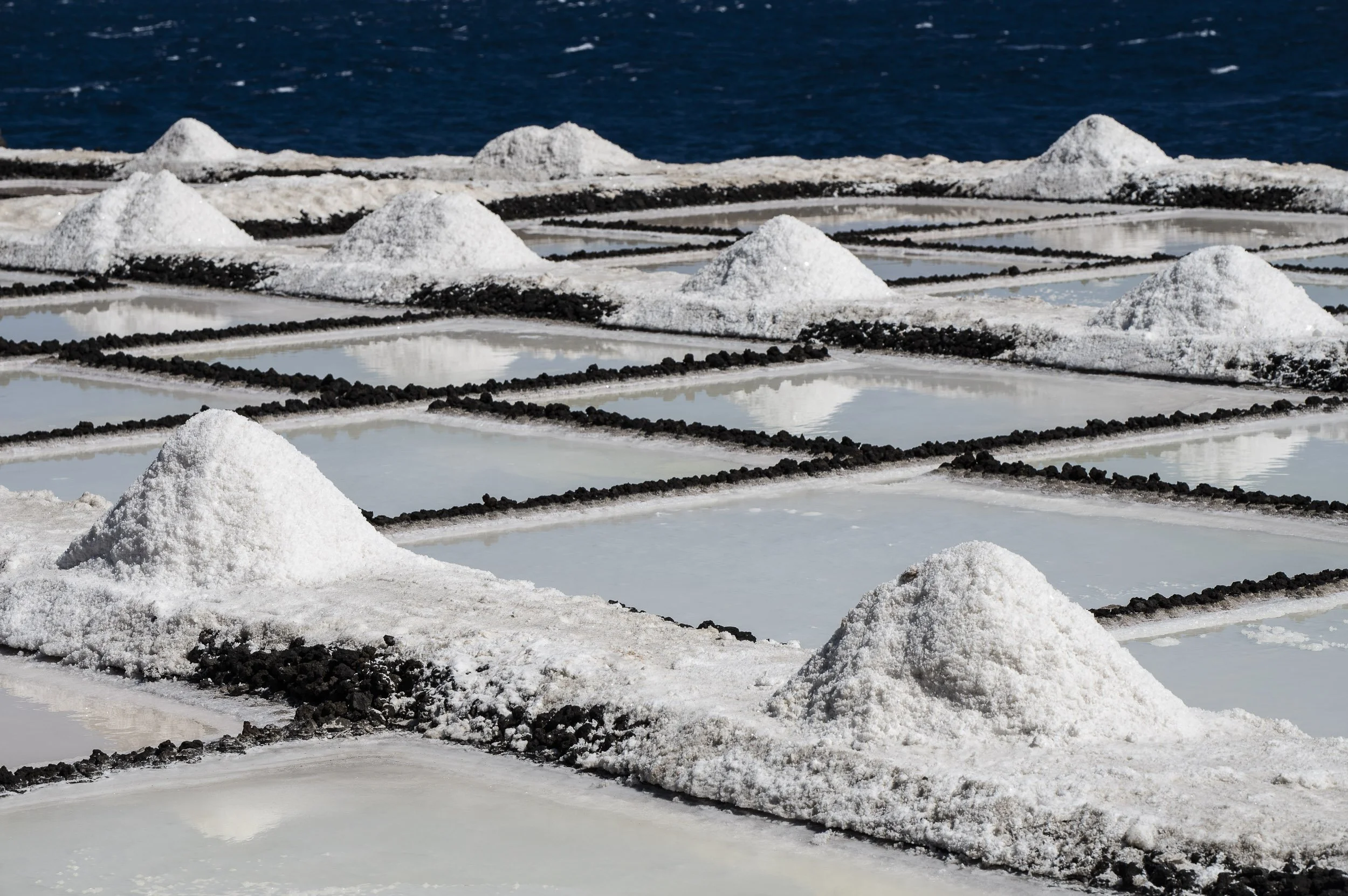 Salinas en La Palma con montículos de sal en un fondo de mar azul