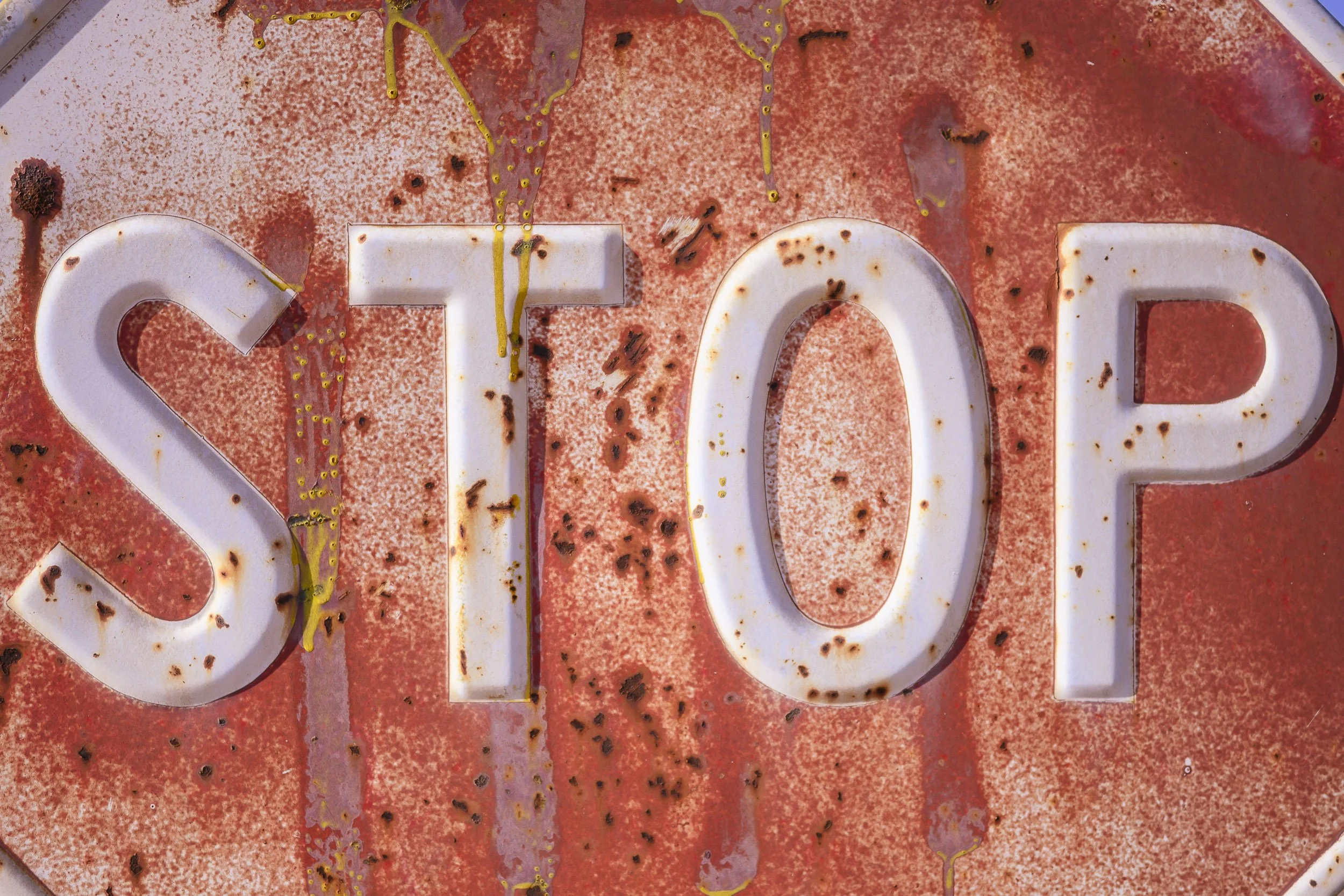 Señal de tráfico que dice 'STOP' con manchas de óxido y mal estado.