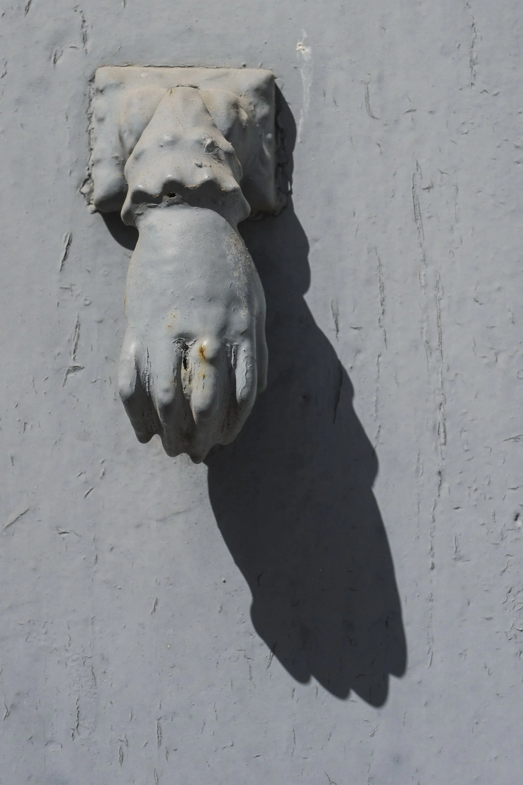 Remate de una tubería de metal en la pared, con sombra en el muro.