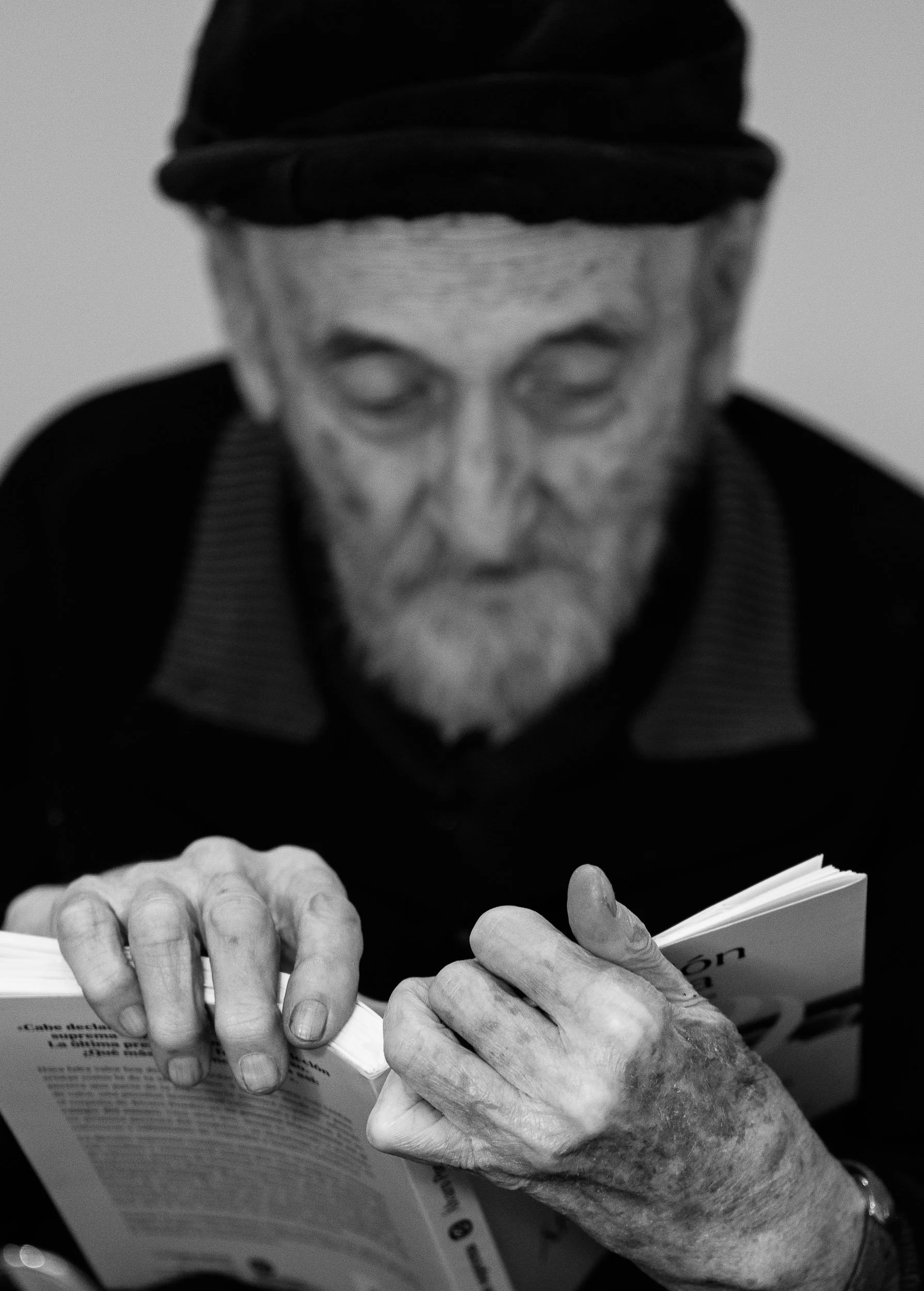 Anciano leyendo un libro con expresión concentrada.