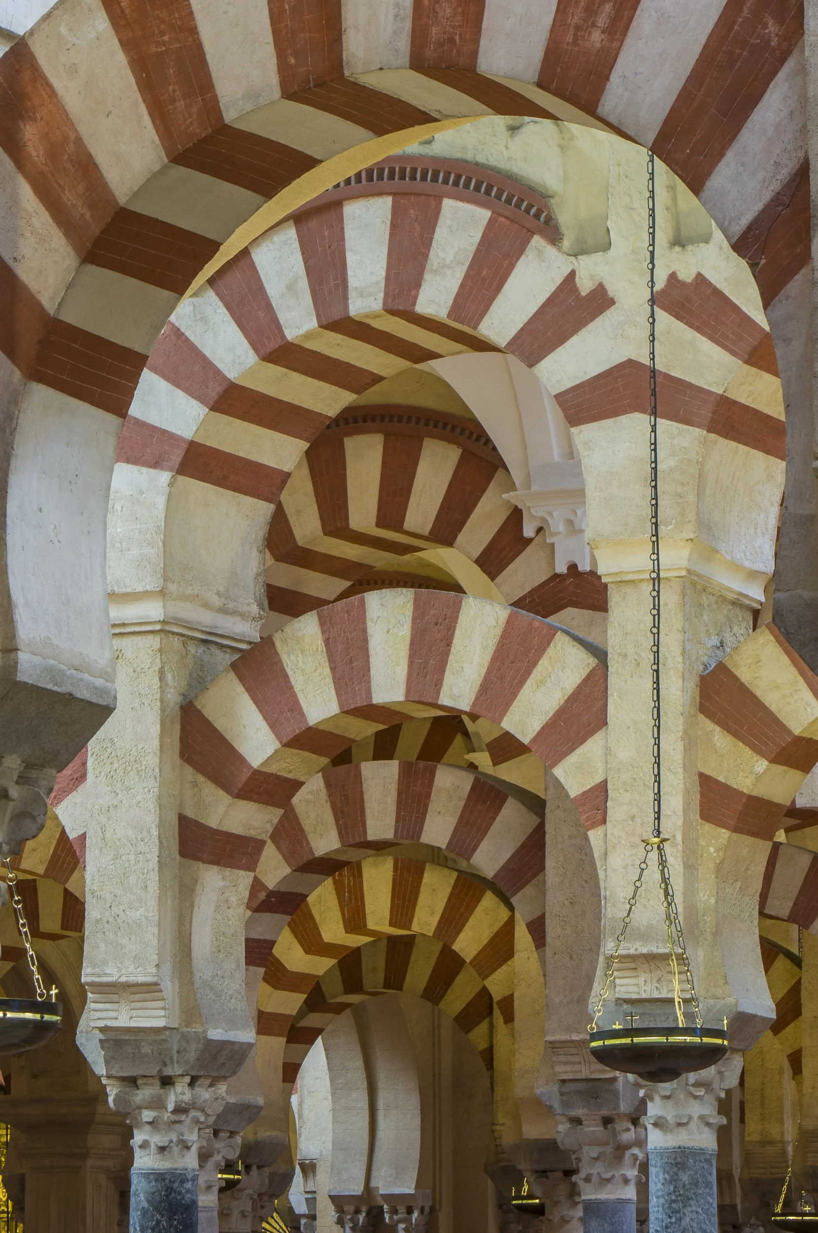 Vista del interior de la Mezquita de Córdoba, con arcos de piedra y ladrillo en espiral, formando un efecto visual de profundidad.