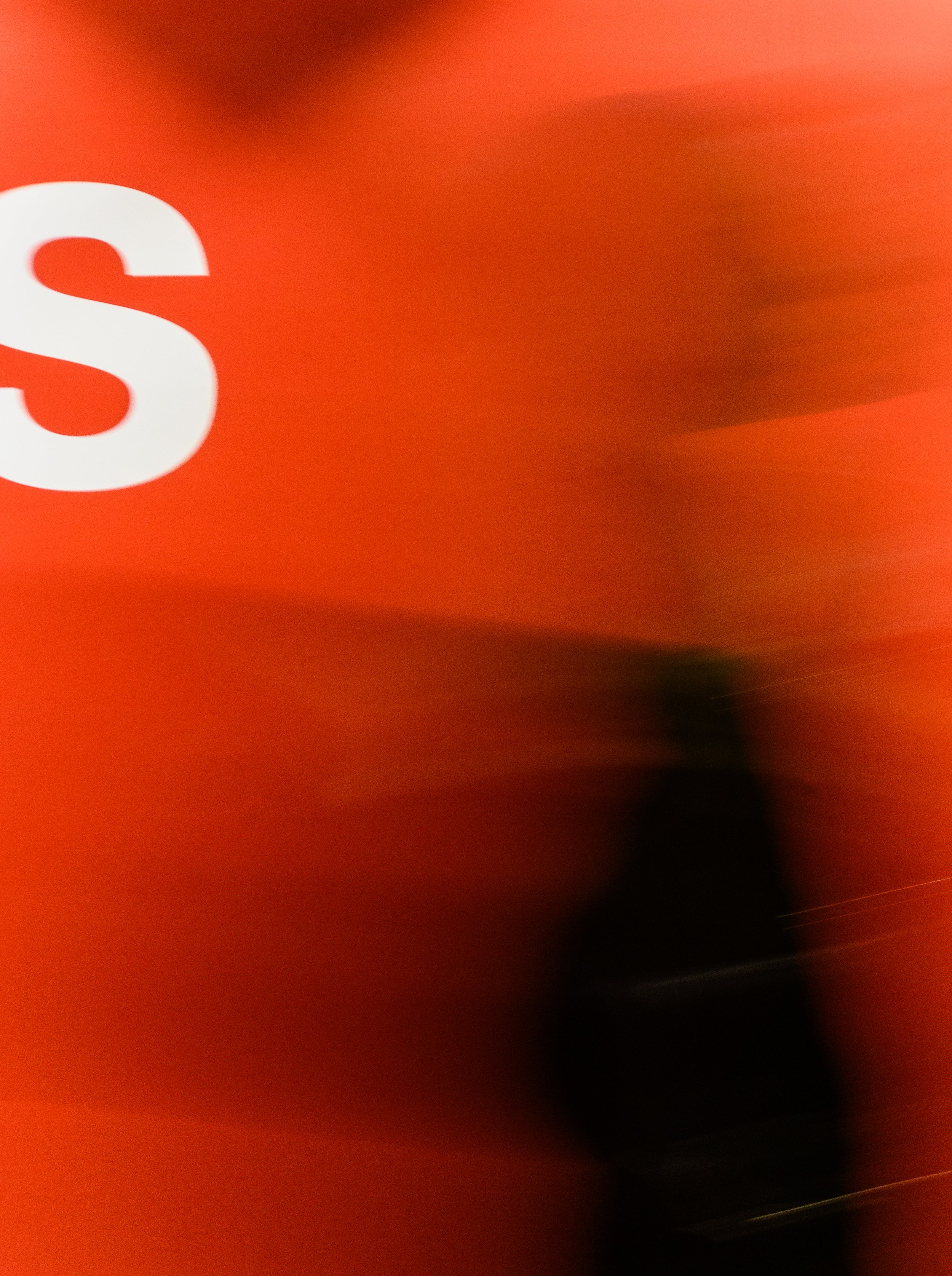 Imagen borrosa con fondo rojo y una letra blanca visible en la parte izquierda.