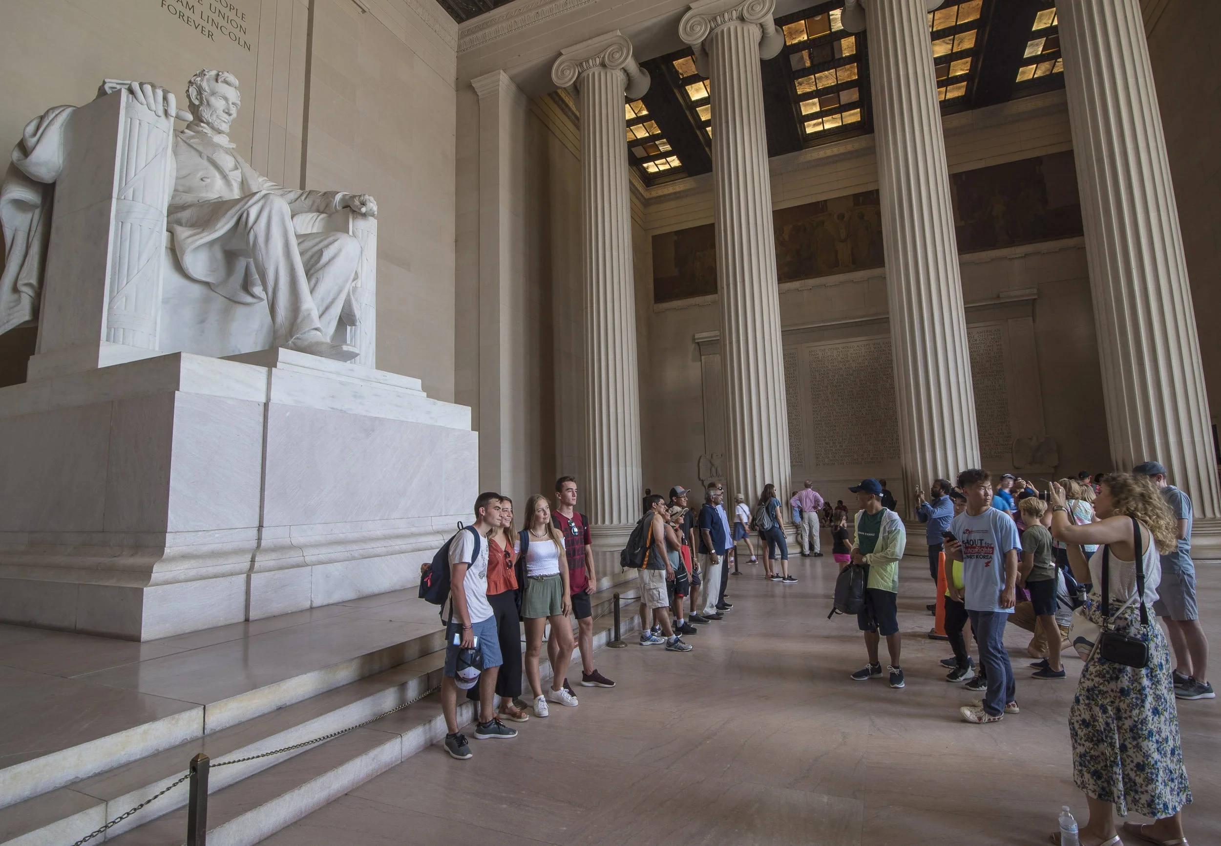 Grupo de turistas en el Museo Nacional de Estadounidenses, con la Estatua de Abraham Lincoln al fondo y columnas gigantes en la sala.