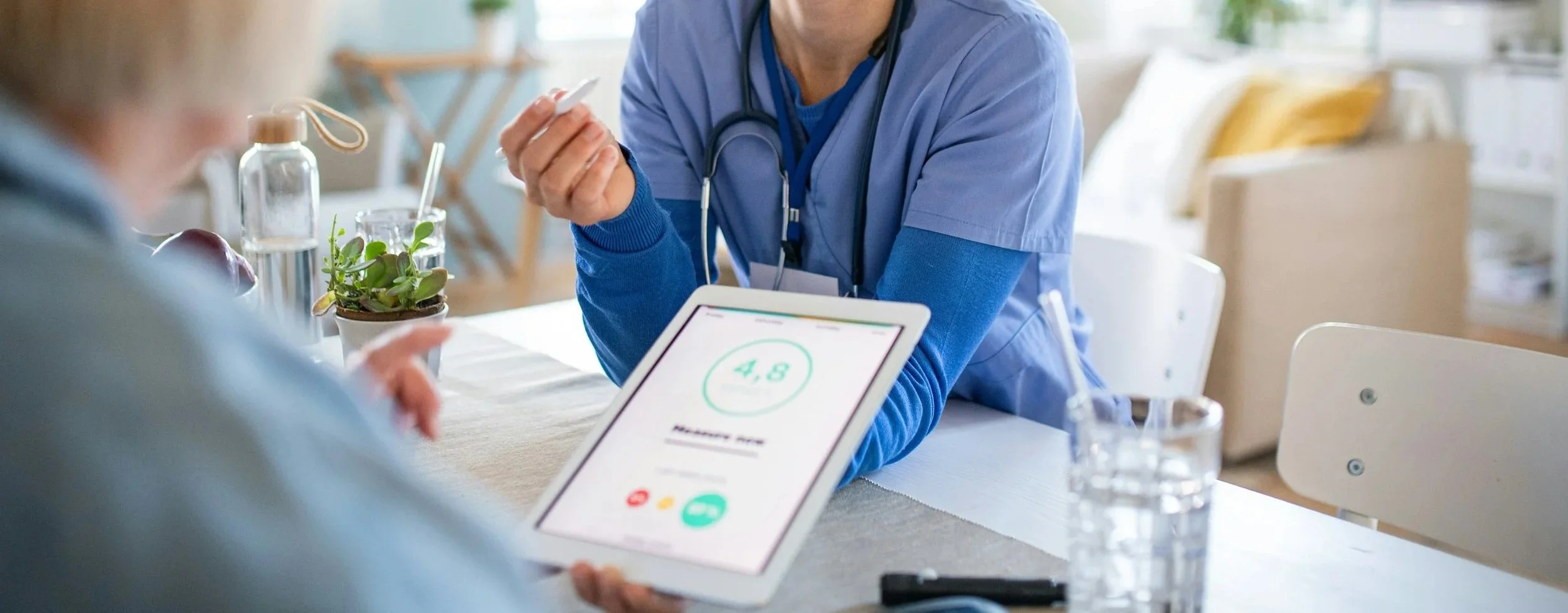 Doctor in scrubs showing a tablet to a patient, with a health score of 4.8 on the screen, in a bright, modern medical office.